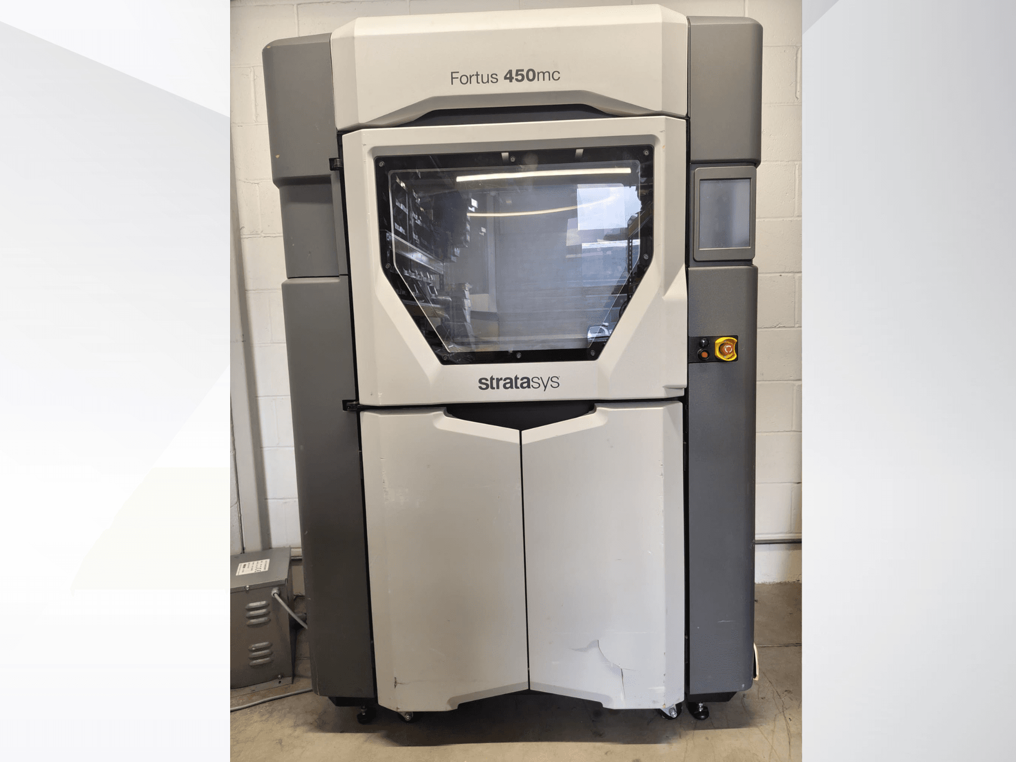 Stratasys Fortus 450mc plastmasas apstrādes iekārta, skats no priekšpuses, ar lielu logu, vadības paneli un rūpniecisko dizainu.