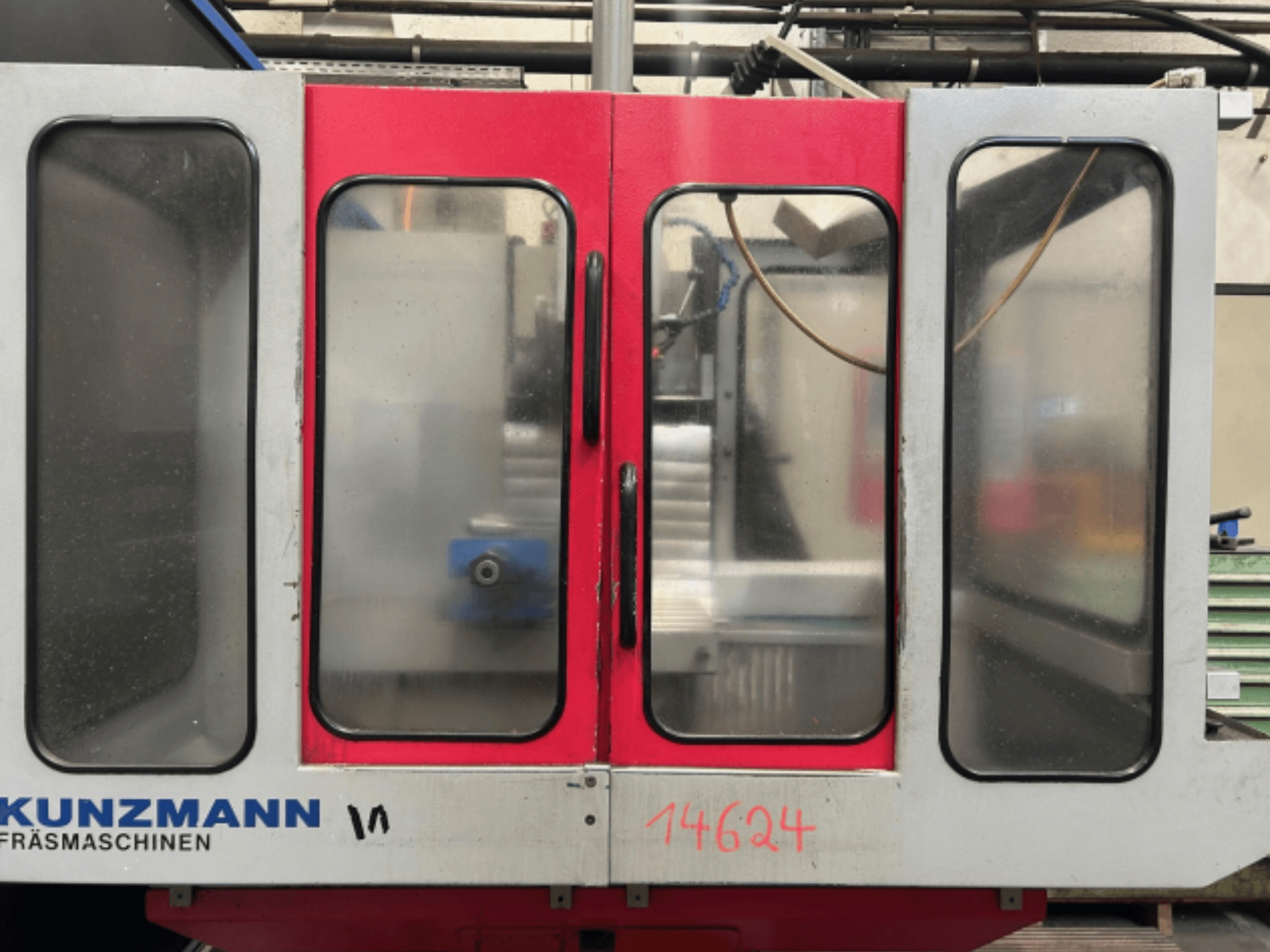 KUNZMANN CNC mašīnas priekšējais skats ar sarkanām un pelēkām paneļiem, ar redzamu vadības paneli un instrumentu turētāju iekšpusē.