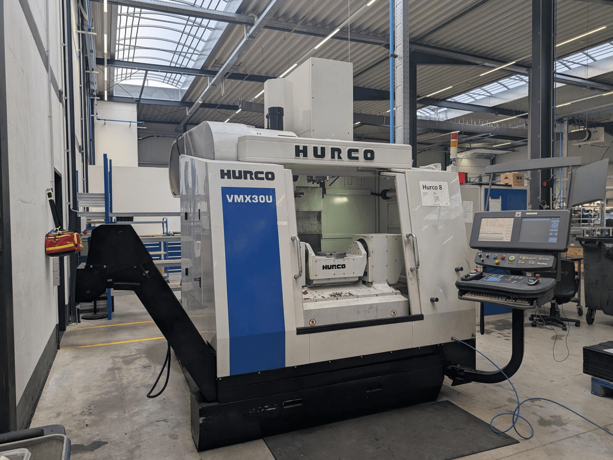 Hurco VMX30U CNC darbnīcā, skats no priekšpuses, ar vadības paneli ar pogām un datu displeju.