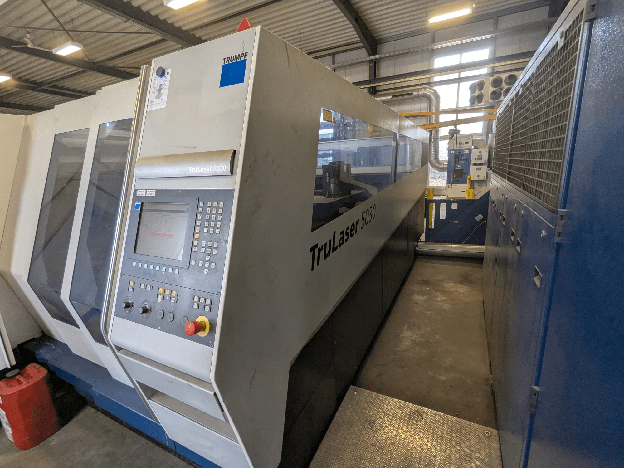 TRUMPF TruLaser 5030 CO2 lāzera griešanas iekārta, priekšējais skats, kurā redzams vadības panelis un glīts dizains, rūpnieciskā vidē.