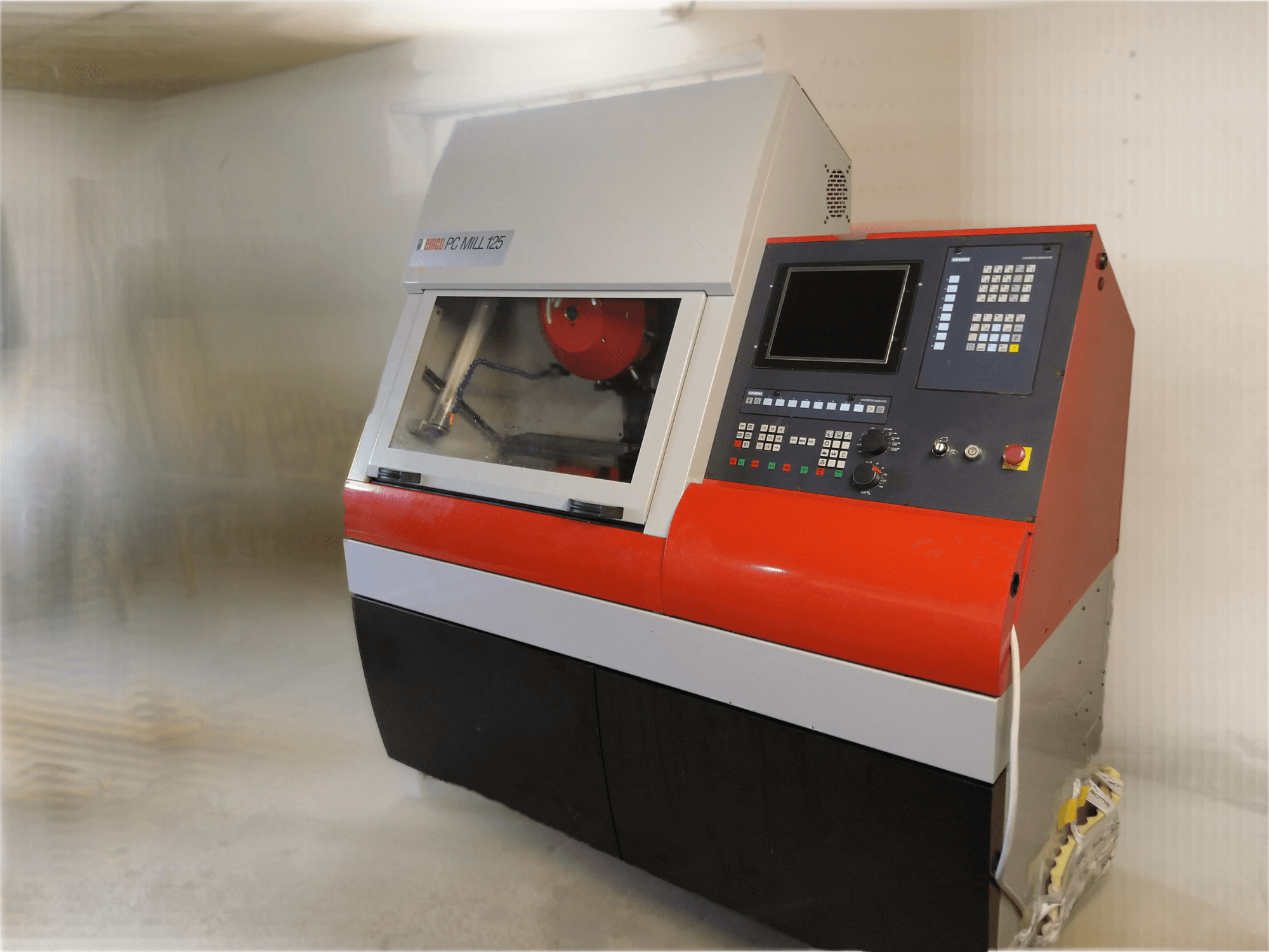 EMCO PC MILL 125 vertikālais apstrādes centrs, priekšējais skats ar vadības paneli un redzamo apstrādes zonu.