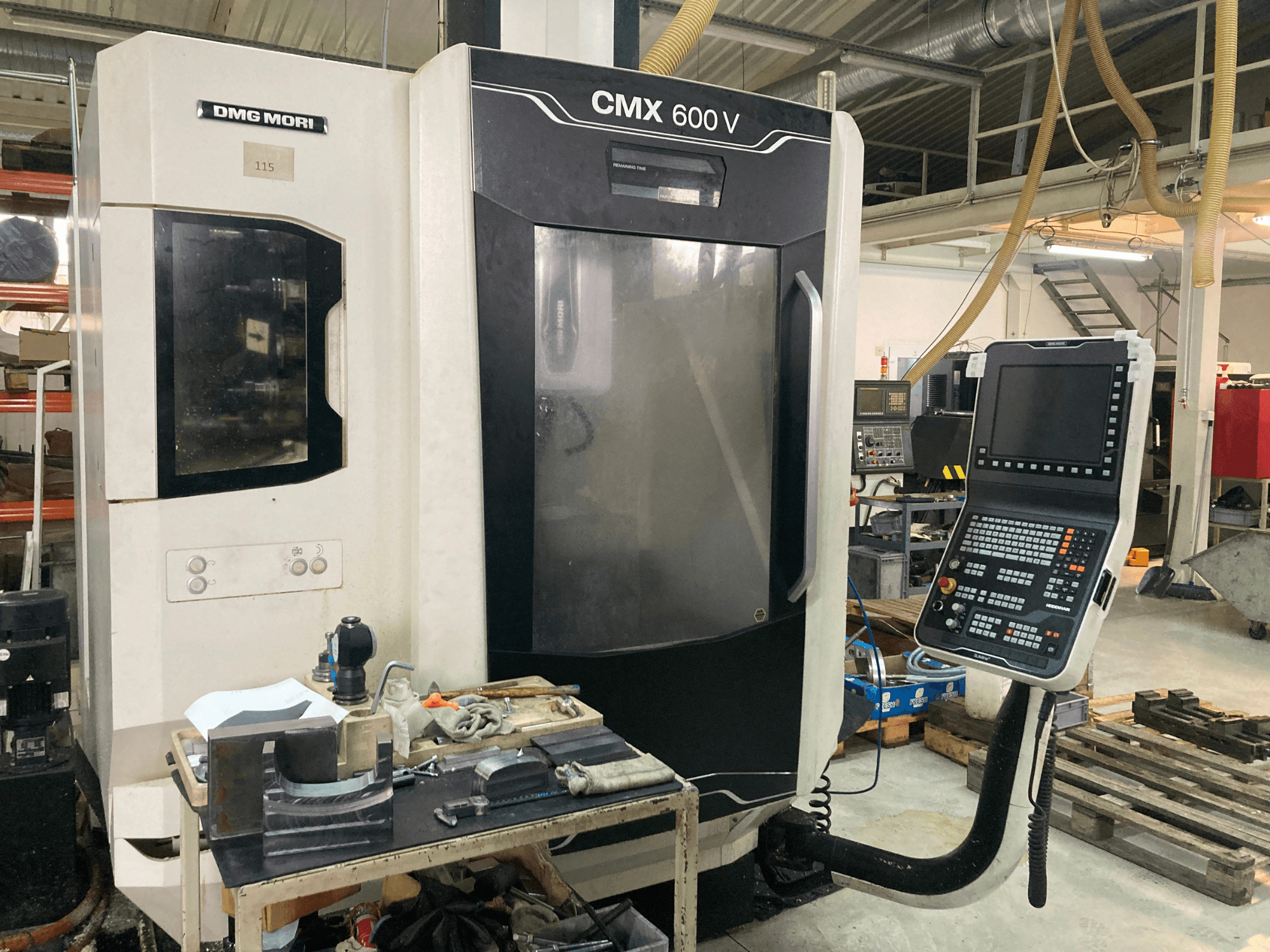 DMG MORI CMX 600 V frēzēšanas iekārta, skatoties no priekšpuses, ar vadības paneli un darbgaldu ar instrumentiem.