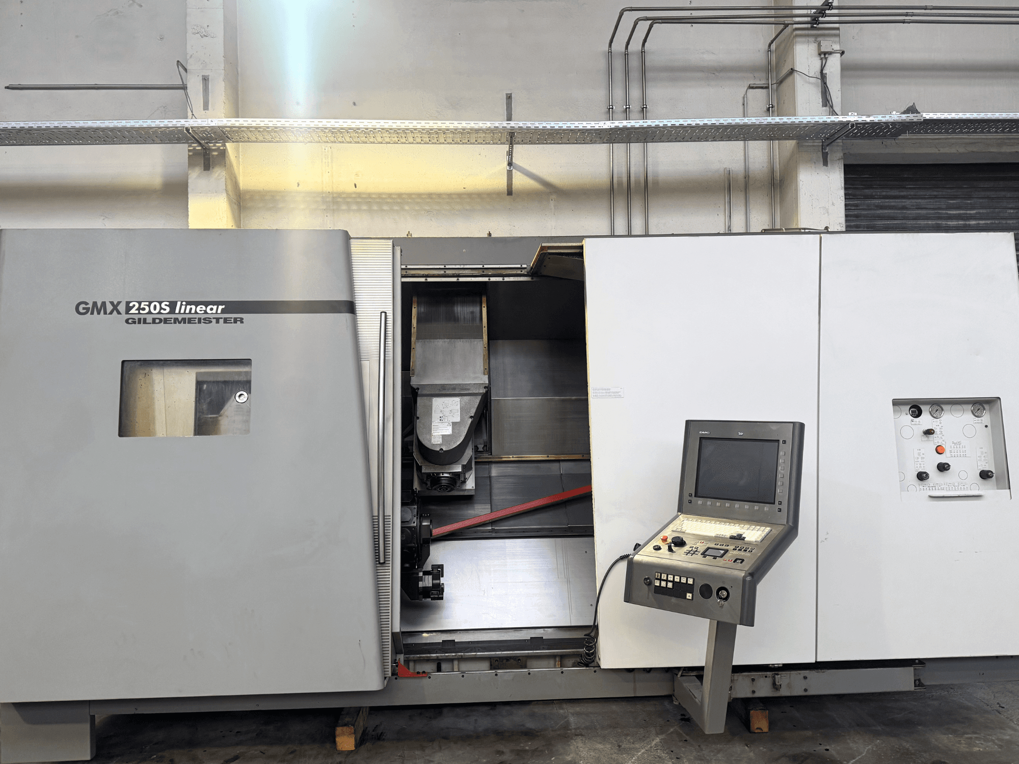 Gildemeister GMX 250S lineārās CNC darbgaldi, skats no priekšpuses, redzams vadības panelis un atvērta darba zona.