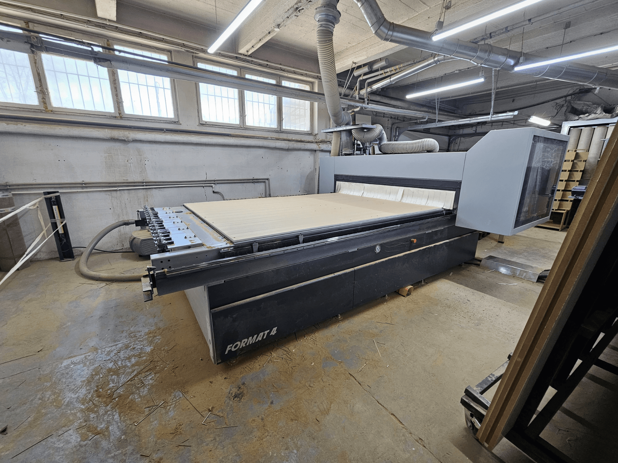 CNC frēze FORMAT4 Profit H80 21.31, sānu skats, kurā redzams lielais darba galds un vadības panelis darbnīcā.