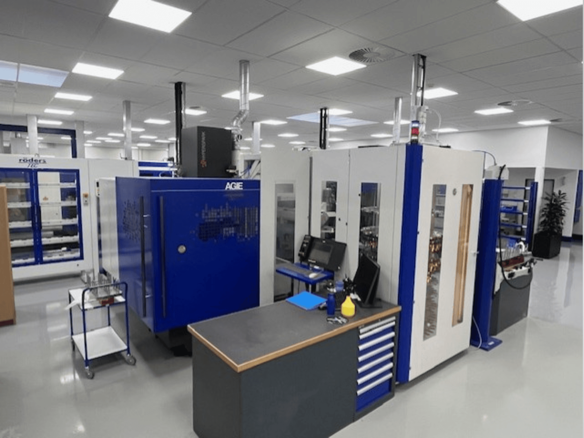 AGIE Hyperspark 2 Precīzas štancēšanas EDM mašīna darbnīcā, parādīta no priekšējā leņķa ar ziliem un pelēkiem akcentiem.