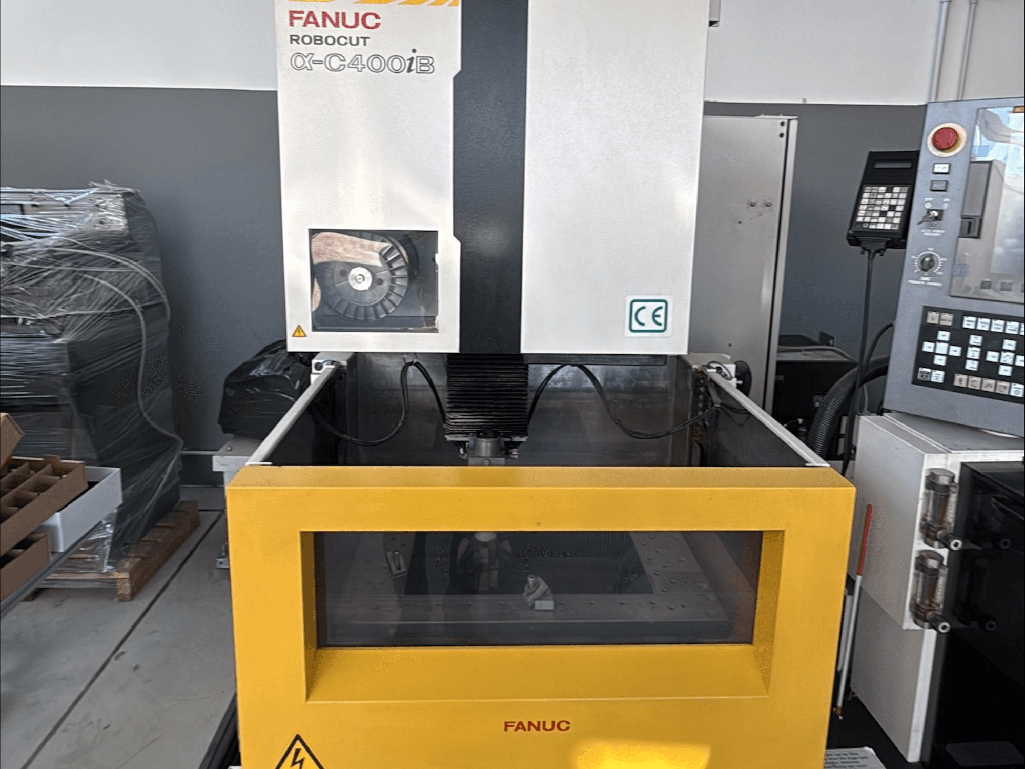 FANUC Robocut α-C400iB stiepļu EDM mašīna, priekšējais skats, ar dzeltenu tvertni un vadības paneli.