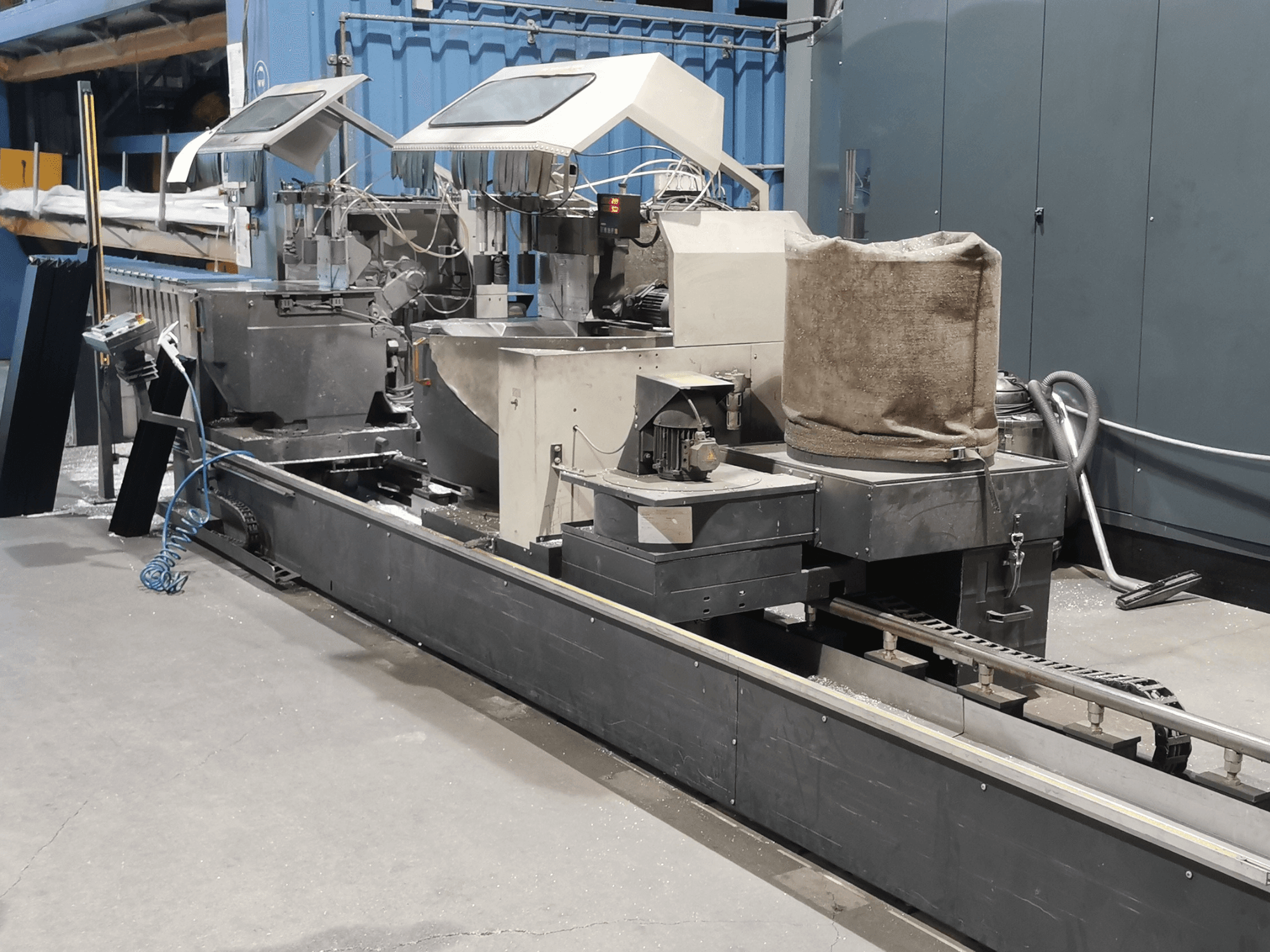 Rūpnieciskās apstrādes iekārta, skatoties no sāniem, ar tvertnēm, konveijera lentēm un vadības paneli rūpnīcā.