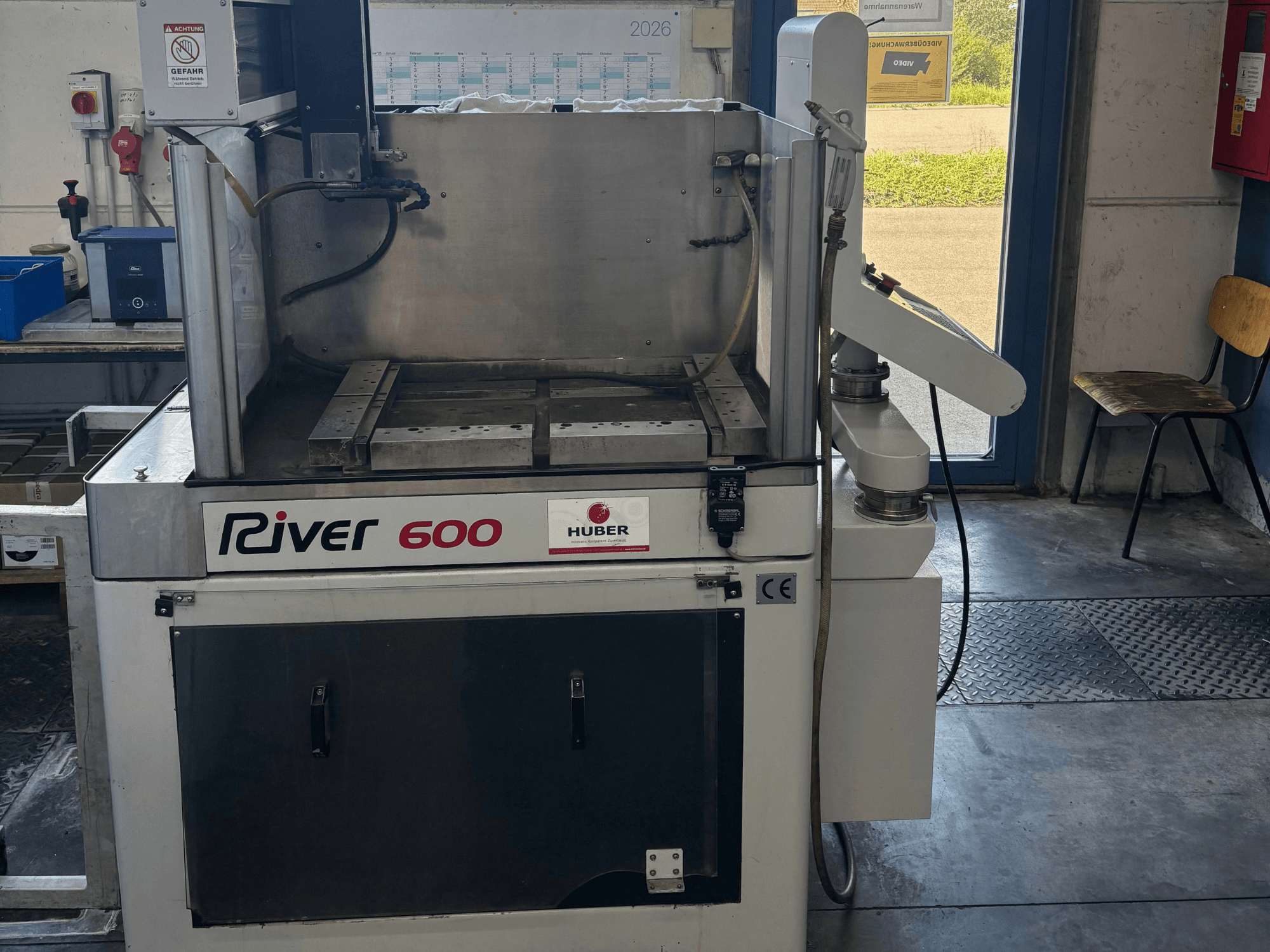 HUBER River 600 CNC dziļumgriešanas elektroerozijas mašīna, skats no priekšpuses, kurā redzama daļēji atvērta darba kamera un vadības panelis.