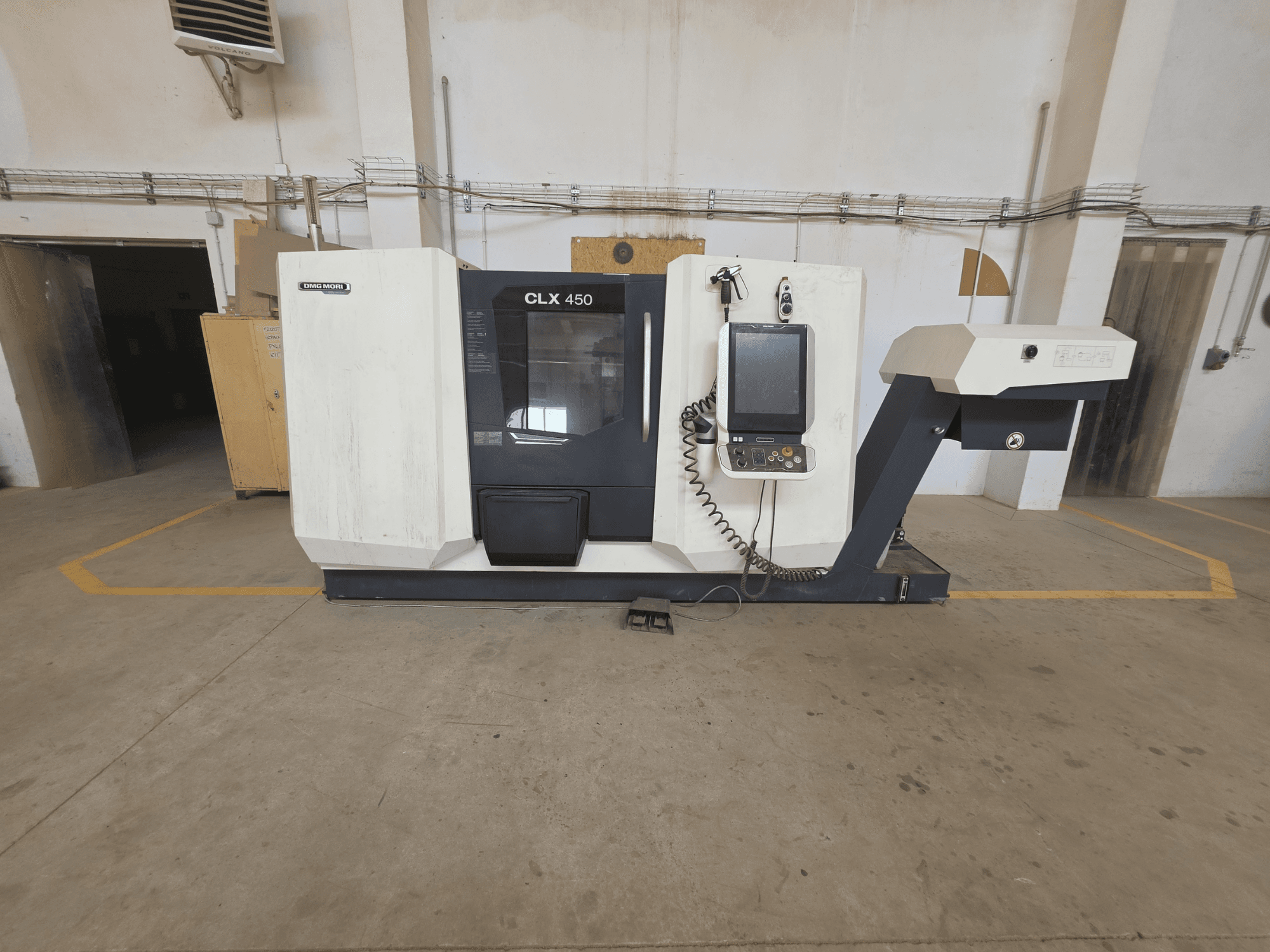 Horizontāls skats uz DMG MORI CLX 450 V4 virpošanas mašīnu ar vadības paneli, vārpstas zonu un tīru industriālo vidi.