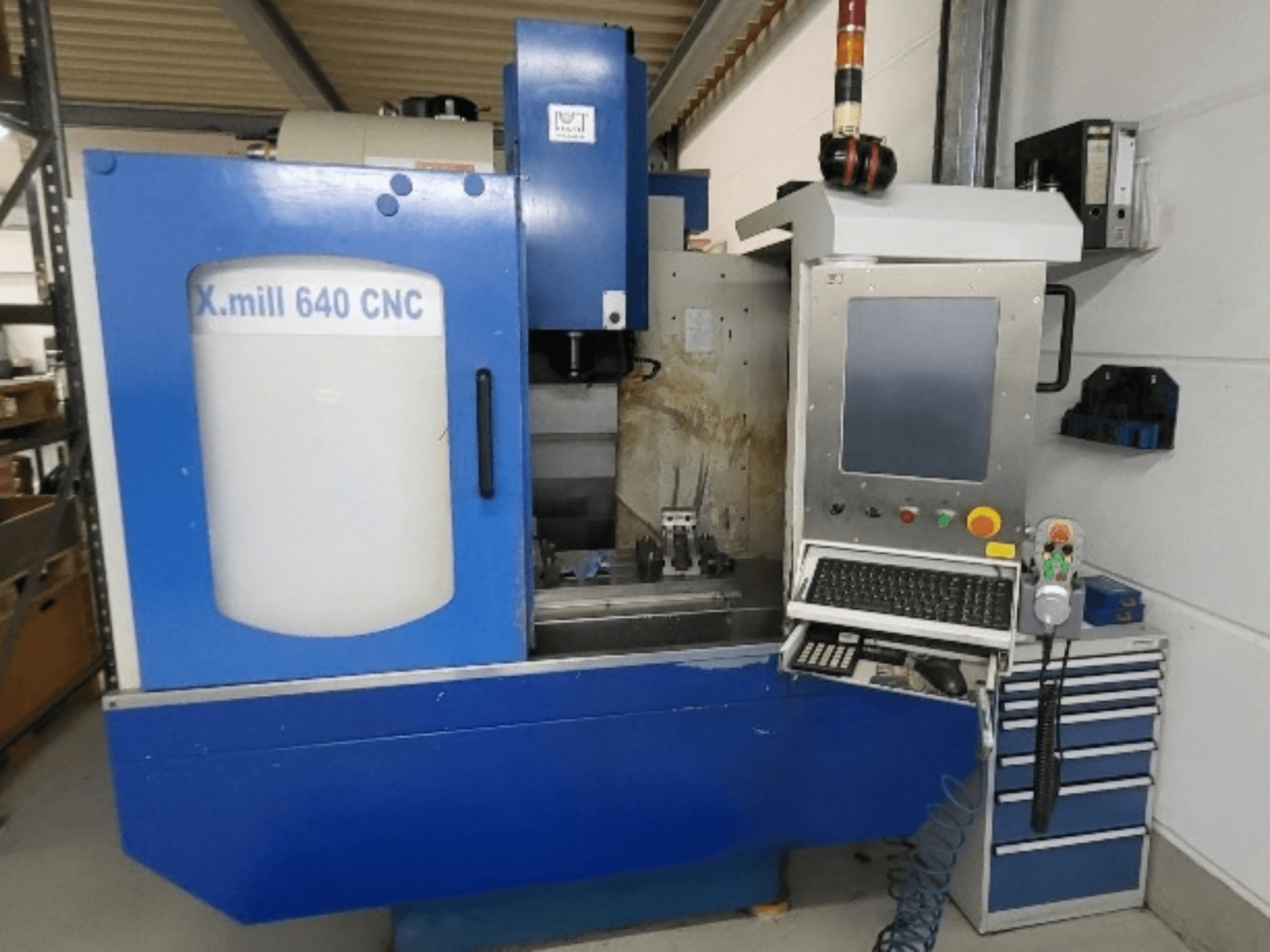 Zils vertikālais CNC apstrādes centrs „KNUTH X-mill 640“, skats no priekšpuses, kurā redzama vadības paneļa un tastatūra.
