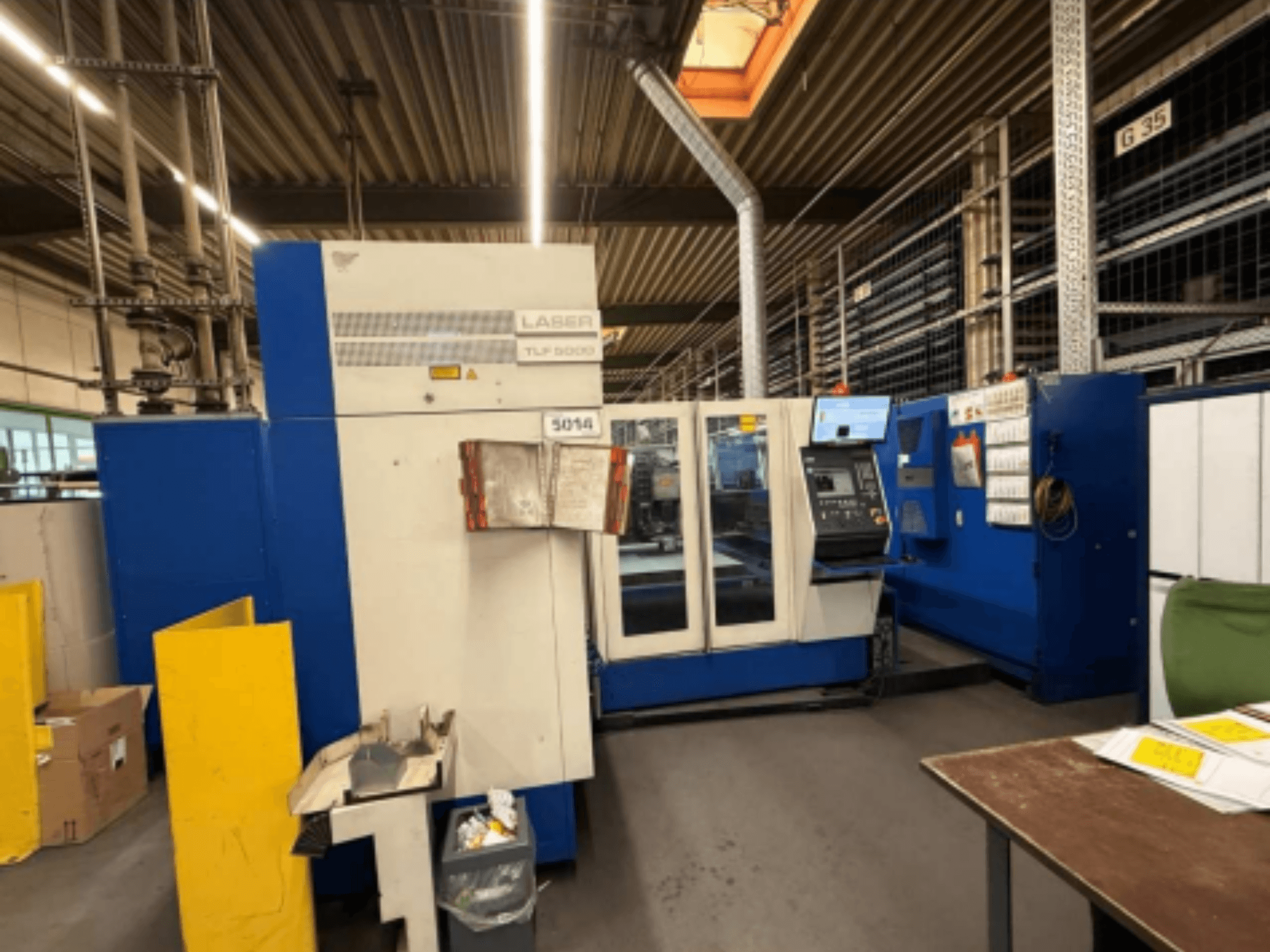 TRUMPF Trumatic L 3050 CO2 lāzera griešanas mašīnas TRUMPF Trumatic L 3050 priekšējais skats, kurā redzams vadības panelis un darbības funkcijas darbnīcā.