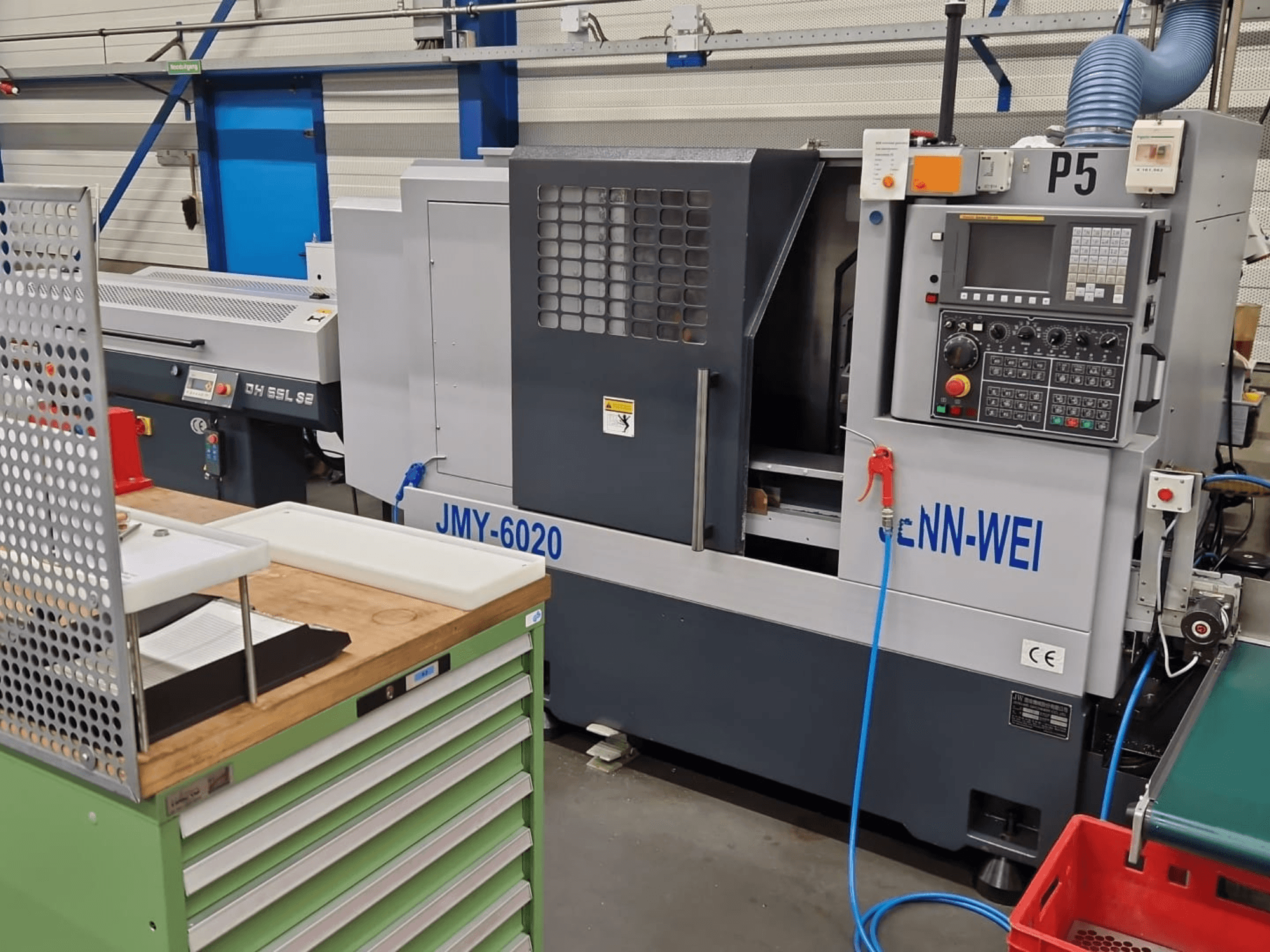 CNC virpas, cNN-WEI modelis JMY-6020, skatīts no priekšpuses. Vadības panelis, avārijas apstāšanās un dzesēšanas šķidruma līnija.