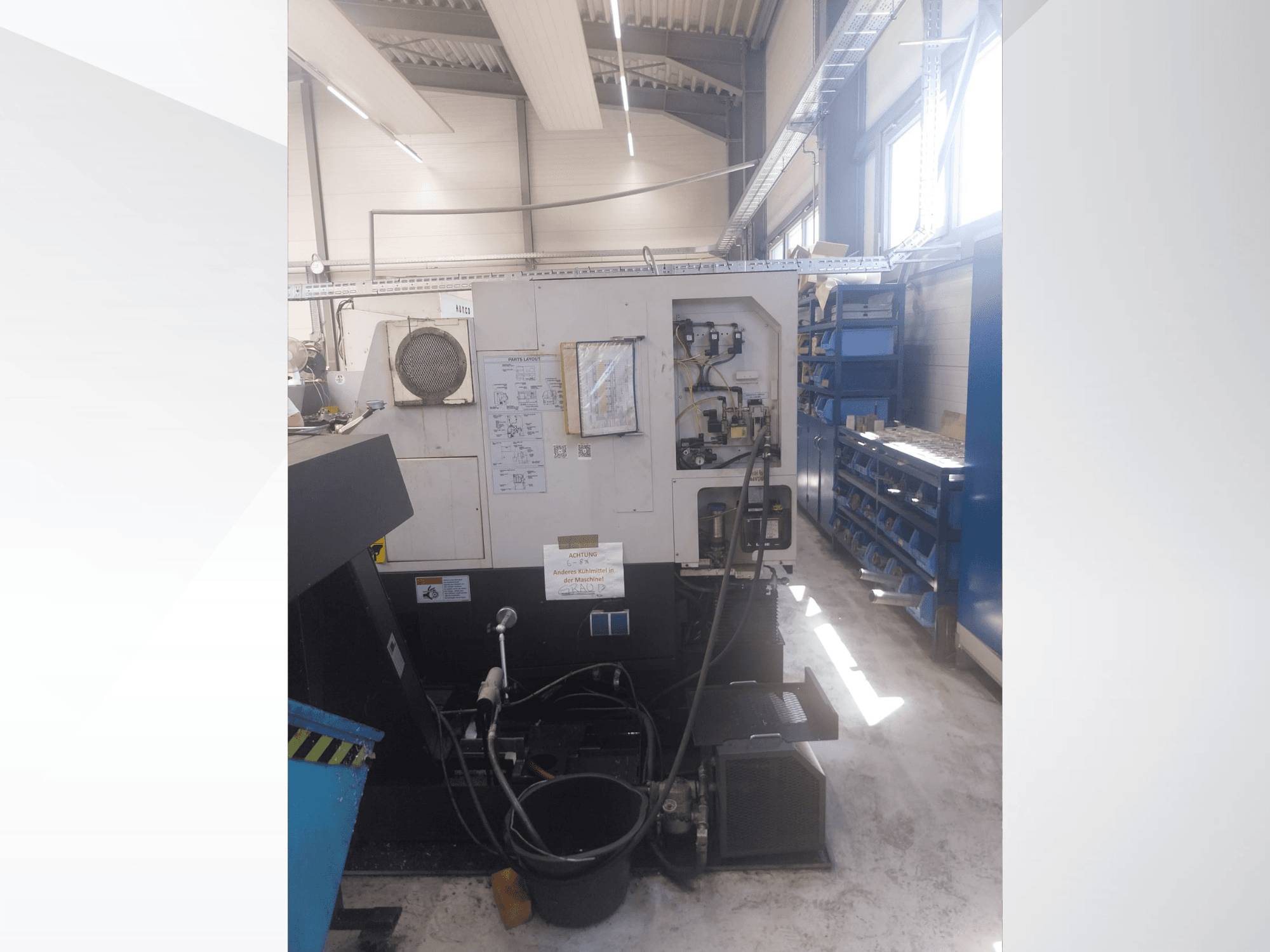 Mazak QUICK TURN NEXUS 200 MS, sānskats, kurā redzams vadības panelis, šļūtenes un instrumentu zona darbnīcas vidē.