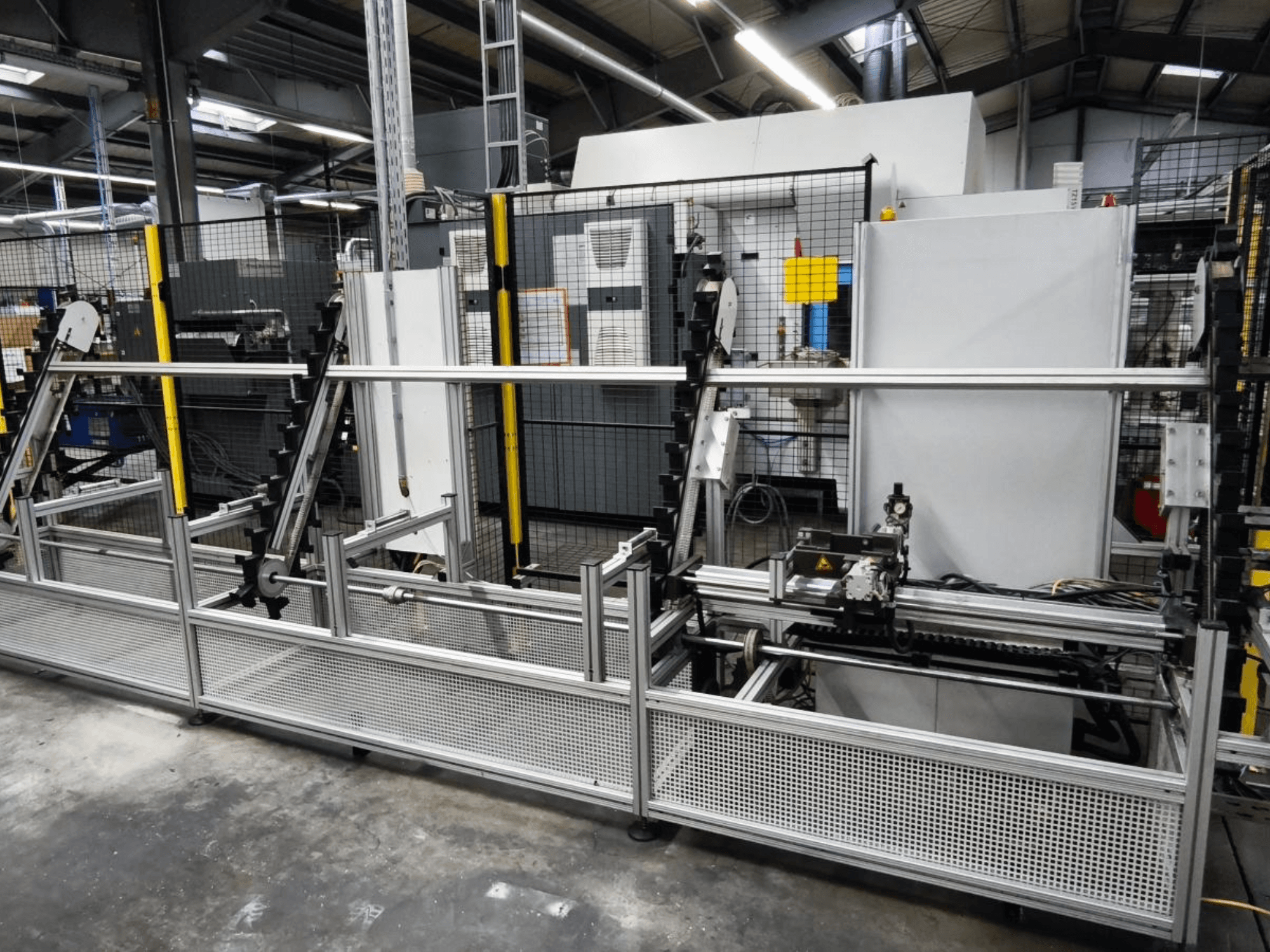 LOHMEIER Schräglademagazin apstrādājamo detaļu pārvietošanas sistēma priekšpusē, kurā redzama tās metāla konstrukcija un integrētās mehāniskās sastāvdaļas.