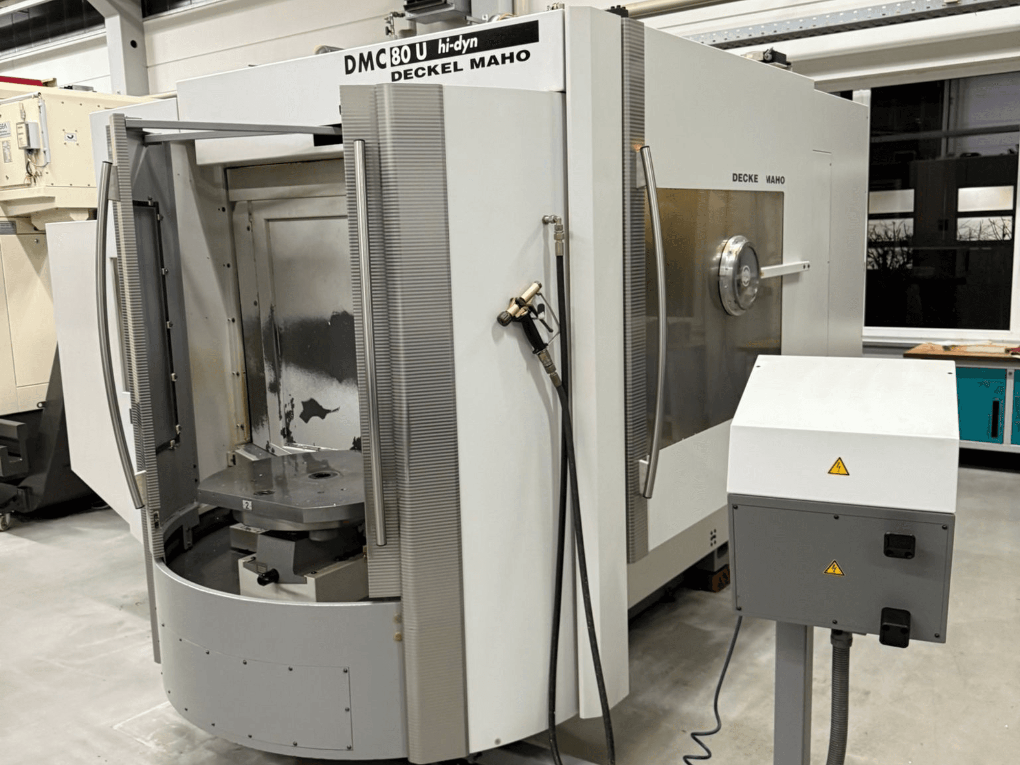 Deckel Maho DMC 80 U ātrgaitas CNC frēzmašīnas priekšējais skats ar atvērtām piekļuves durvīm un vadības paneli sānos.