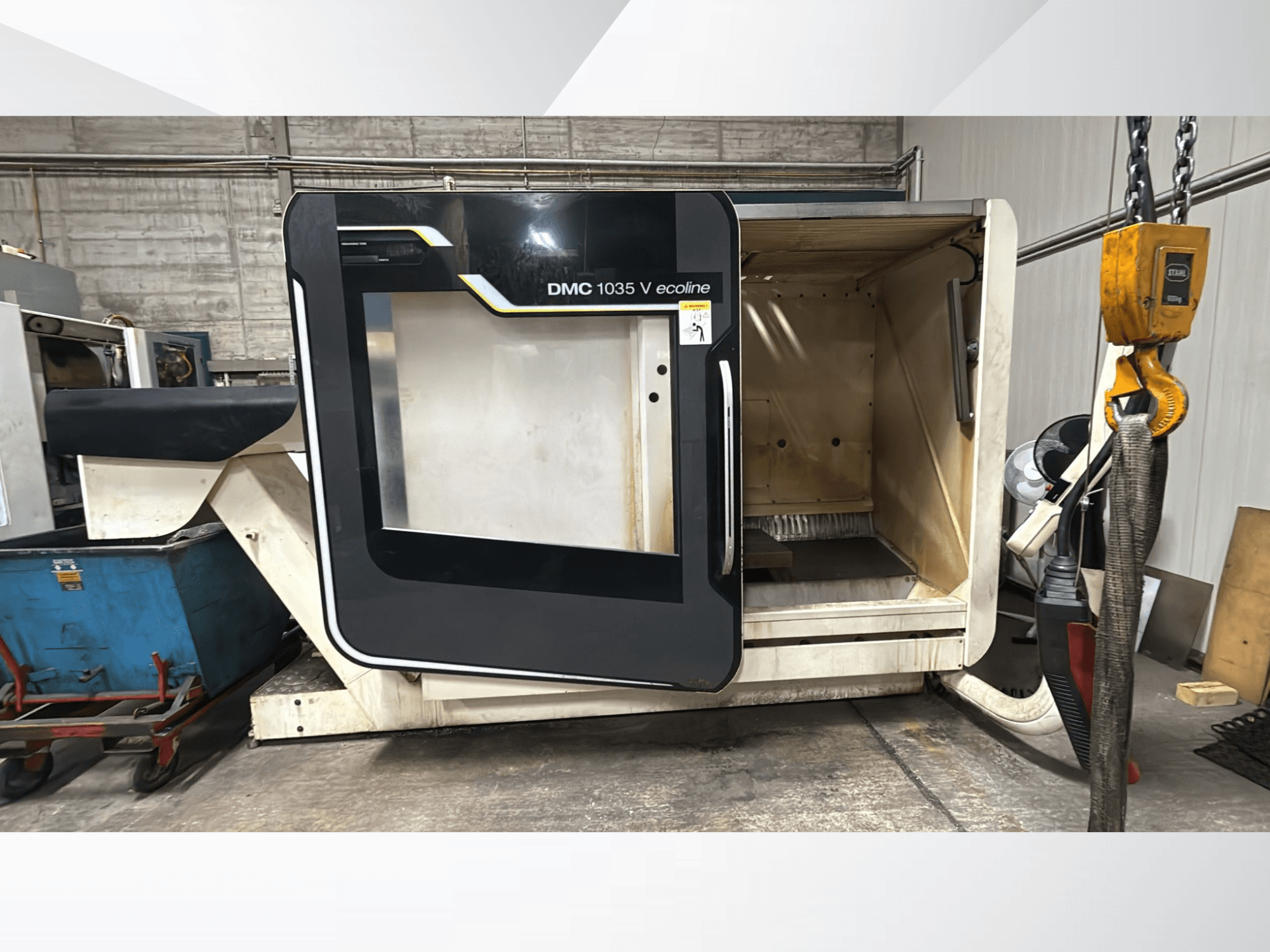 DMC 1035 V ecoline CNC mašīna, skats no priekšpuses, atvērtas durvis atklāj tukšu iekšpusi un vadības paneli.