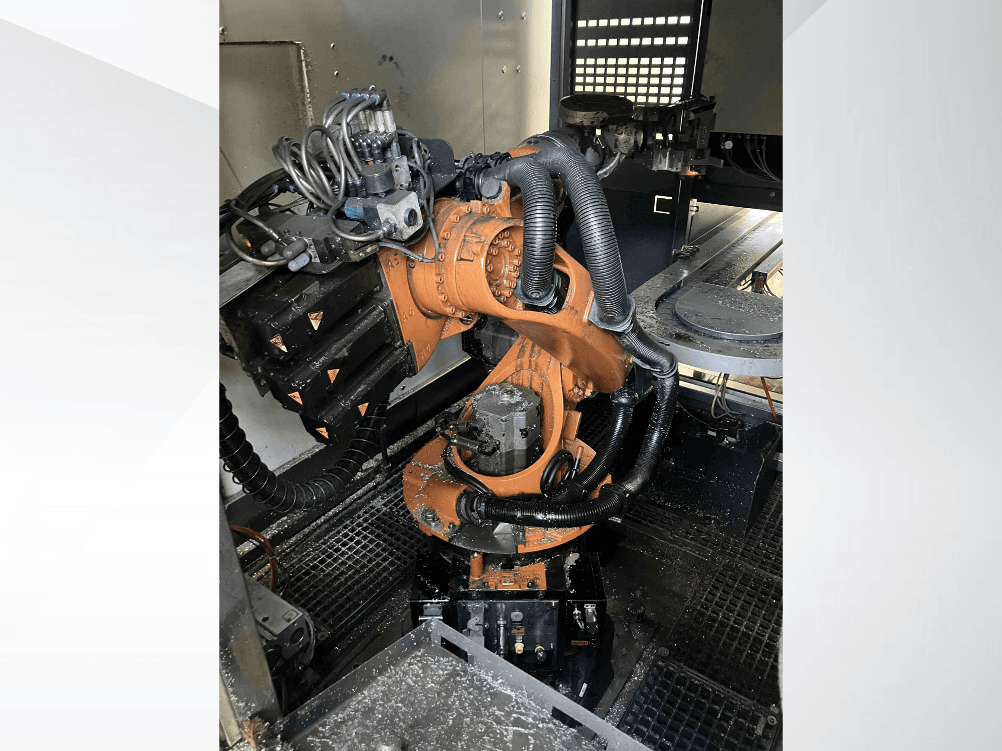 KUKA KR 16 robota roka no augšējā leņķa, kurā redzami mehāniskie komponenti un elektroinstalācija darbnīcas vidē.