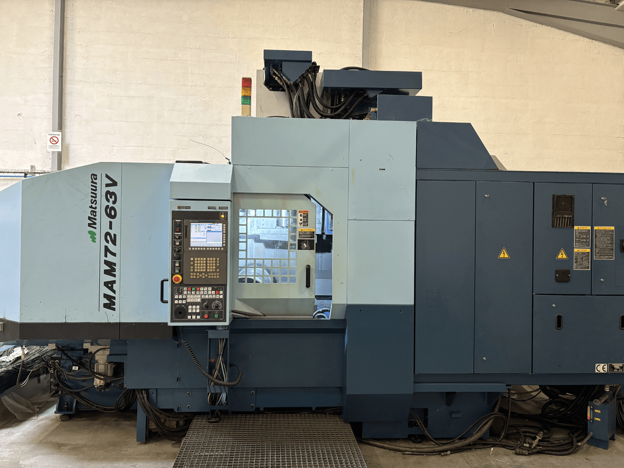 Matsuura MAM 72-63 V vertikālais apstrādes centrs, priekšējais skats, kurā redzams vadības panelis un drošības elementi.