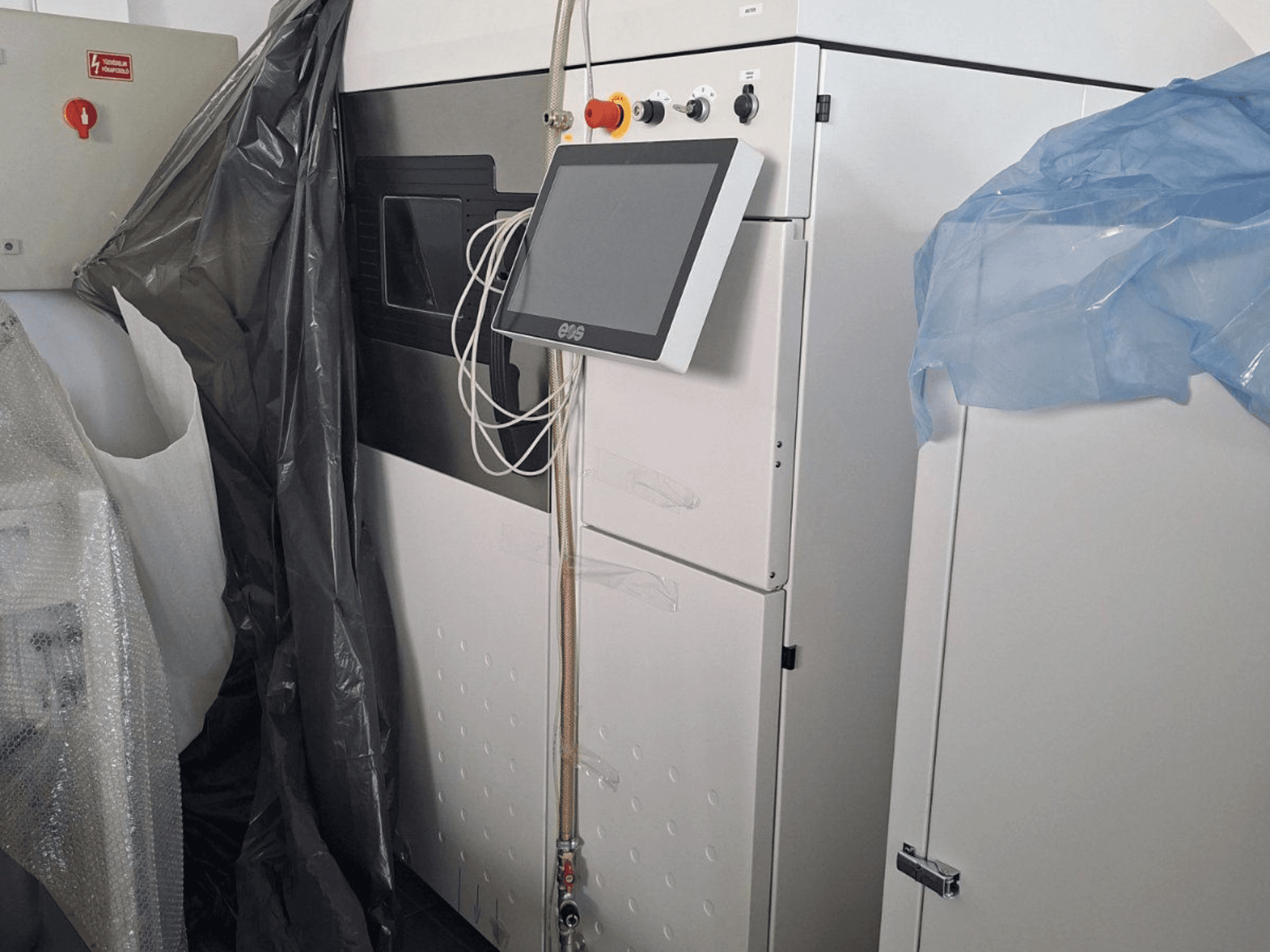 EOS M 290 metāla 3D printera priekšējais skats no priekšpuses ar skārienjūtīgo ekrānu, vadības paneli un aizsargpārklājumu.