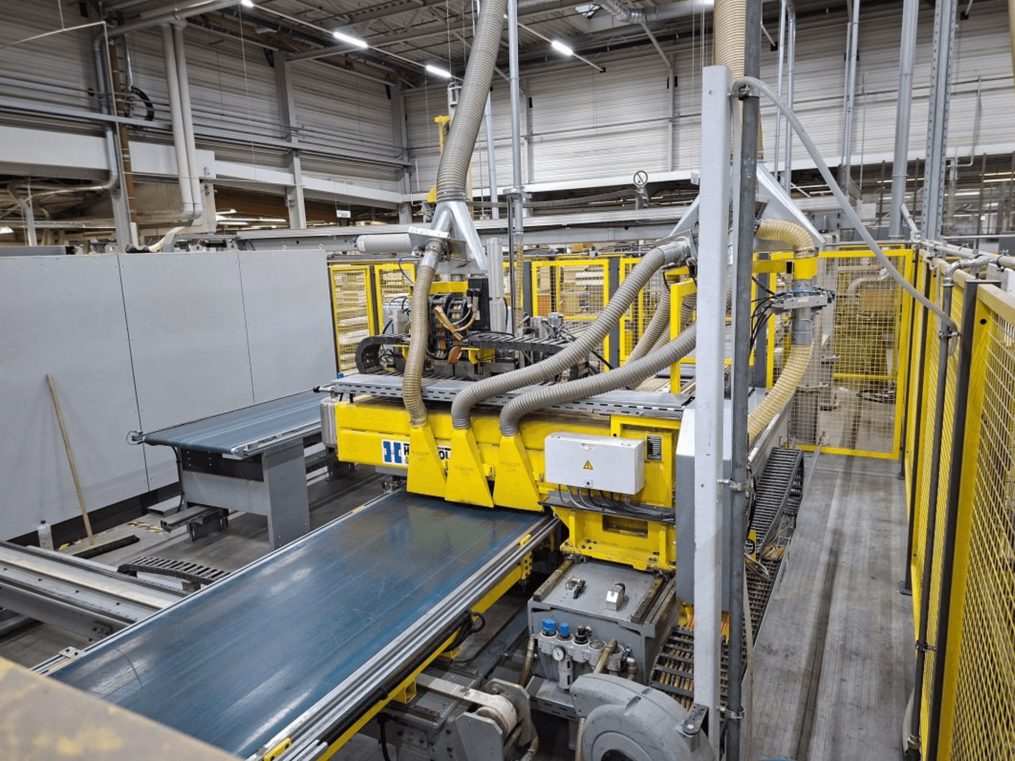 Rūpnieciskā konveijera sistēma no sānu skata ar dzeltenām mašīnām, vadības paneli un šļūteņu stiprinājumiem ražošanai.