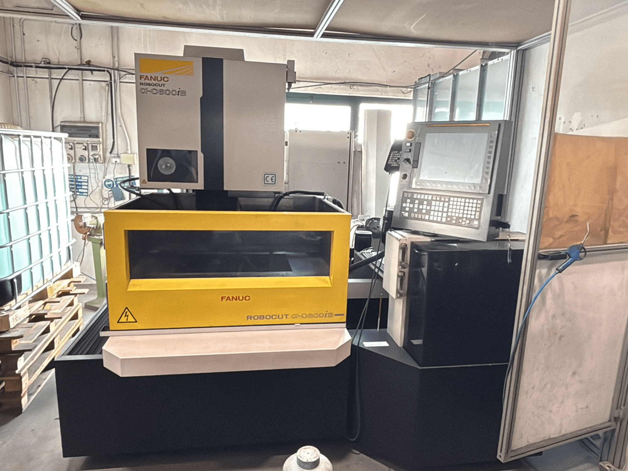 FANUC Robocut α-0iE CNC mašīnas priekšējais skats ar dzeltenu korpusu, kurā redzams vadības panelis un displejs.