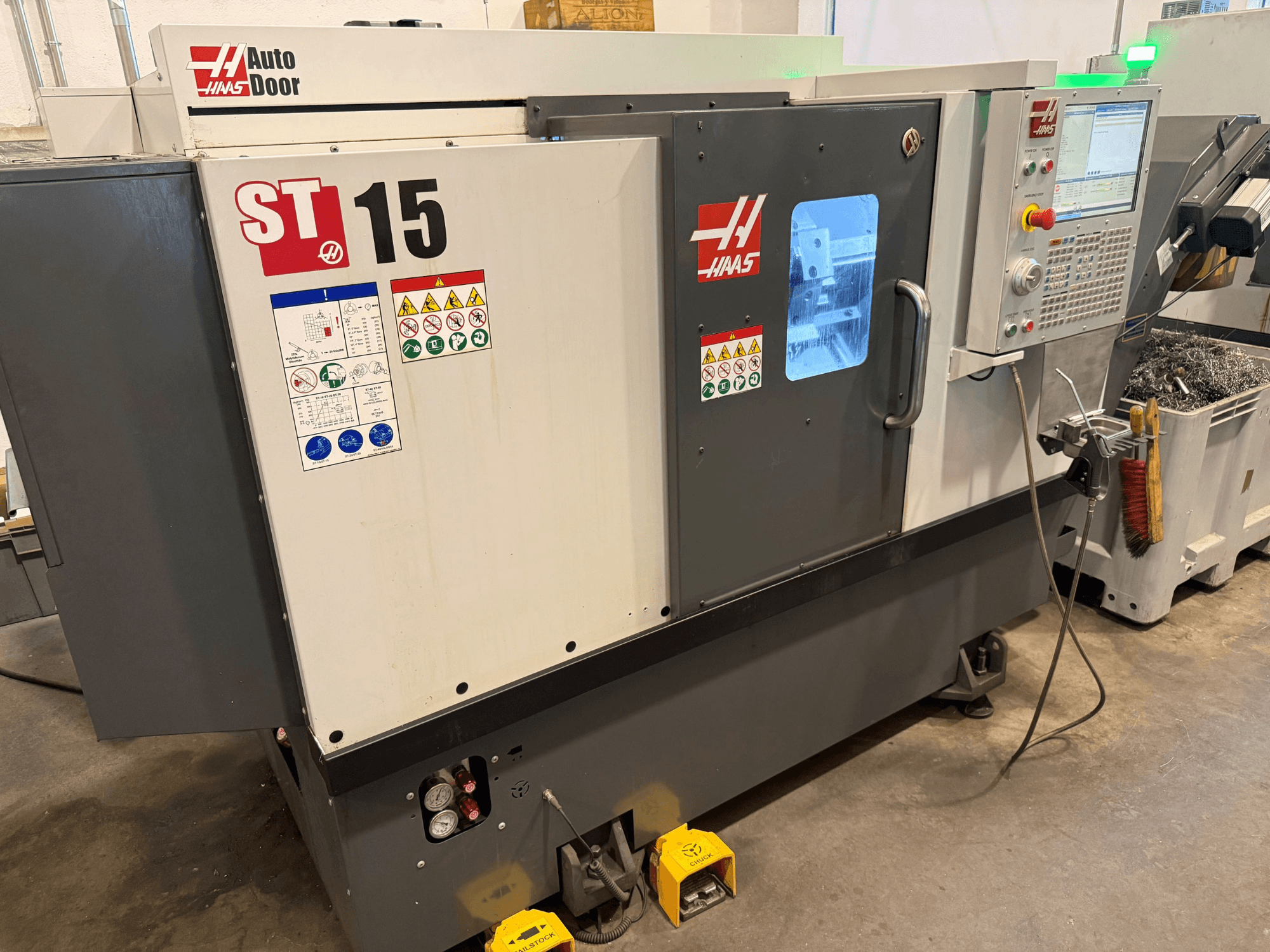 HAAS ST 15 horizontālā virpošanas stende, skats no priekšpuses, kurā redzams vadības panelis, automātiskās durvis un tehniskie rādītāji.