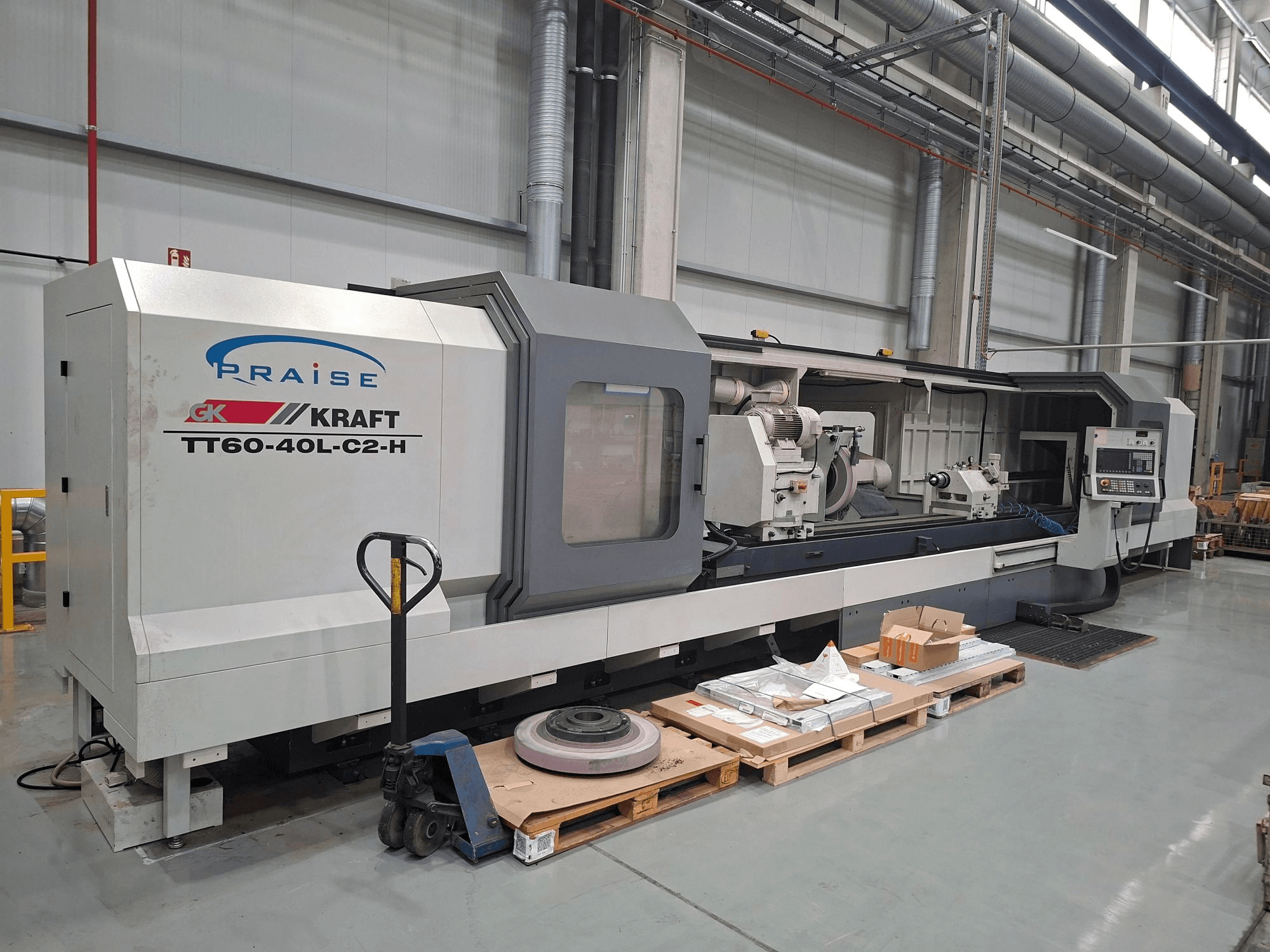 KRAFT TT60-40L-C2-H cilindriskā slīpēšanas mašīna, skats no sāniem, kurā redzami vadības elementi un slīpēšanas disks darbnīcas vidē.