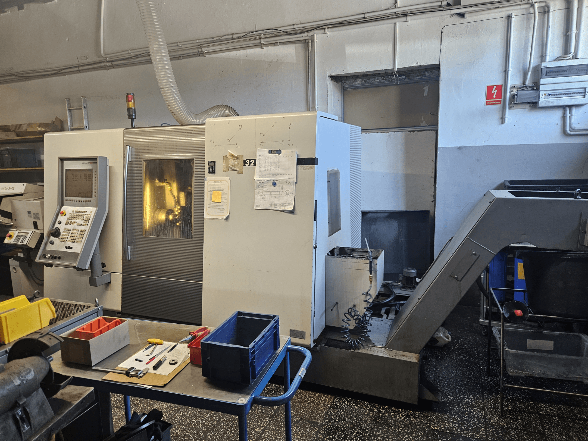 Daudzvārpstu virpošanas mašīna DMG GILDEMEISTER Sprint 32 lineārā, priekšējais skats darbnīcā, redzams vadības panelis un instrumenti.