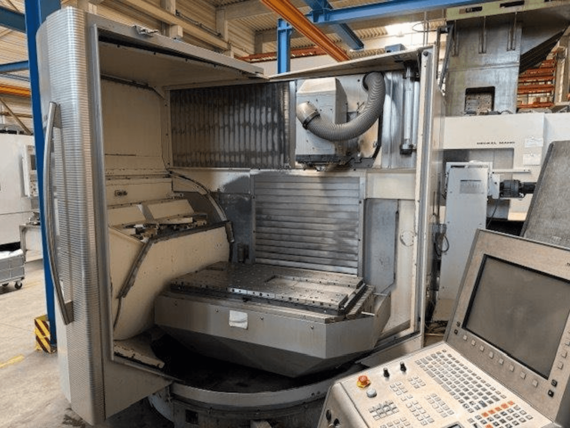 DMG MORI DMU 80T vertikālais apstrādes centrs, priekšējais skats, kurā redzams atvērts korpuss un vadības panelis.