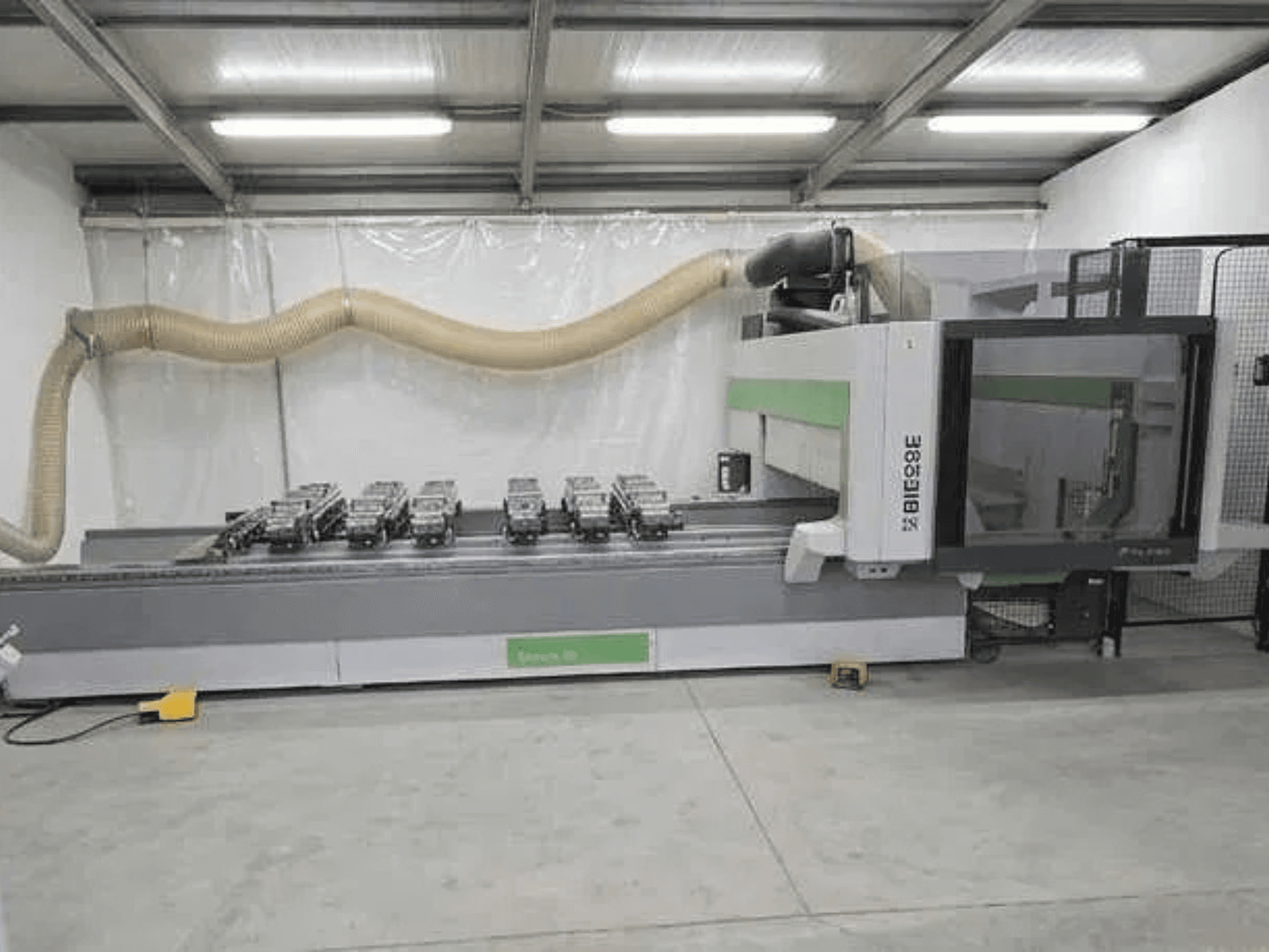 BIESSE Rover K1232 CNC apstrādes centrs, skats no sāniem, kurā redzamas vakuuma piesūcējkausītes un putekļu nosūces sistēma.