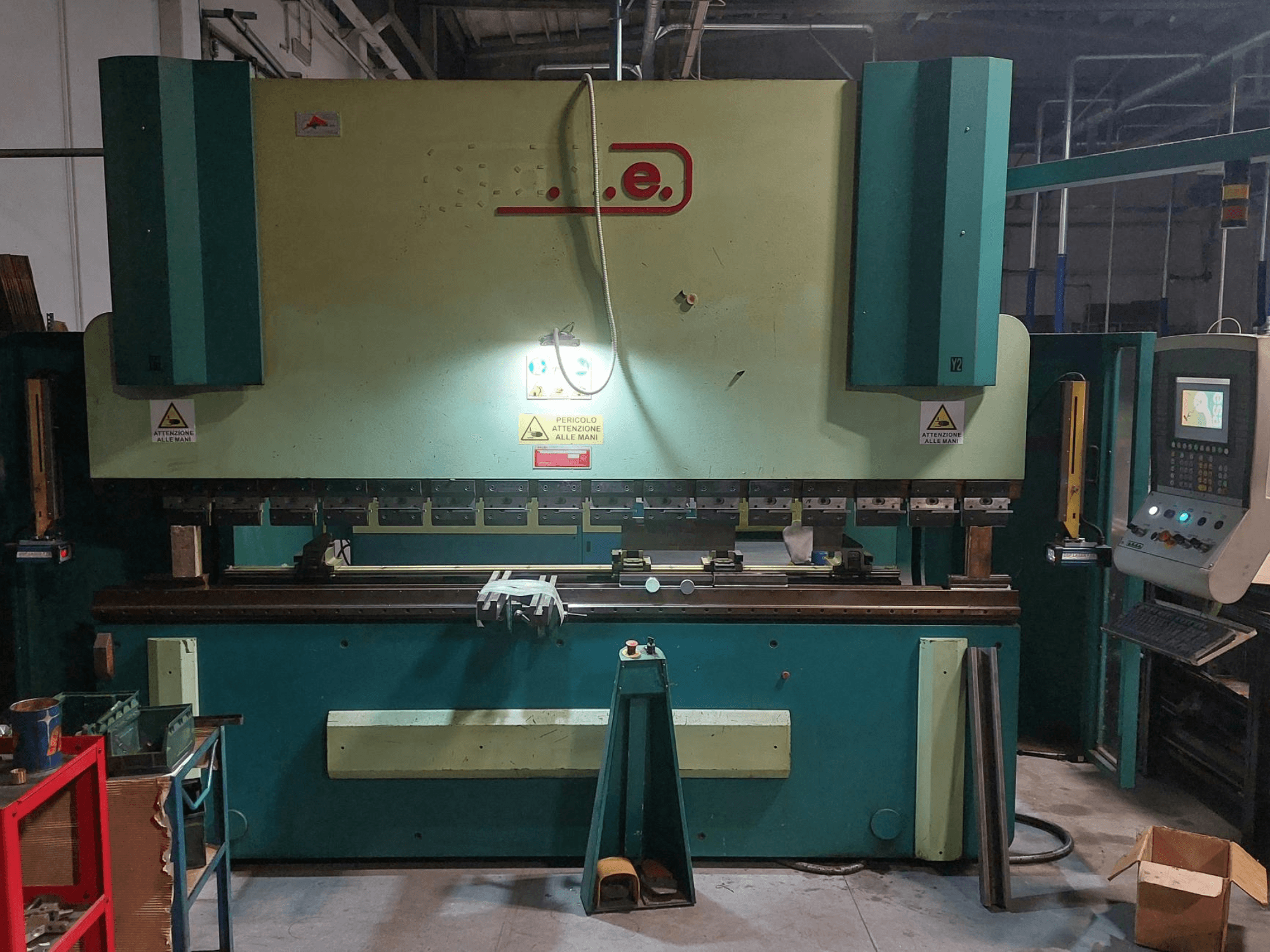 Gade PS-C 3120 lieces preses skats no priekšpuses, kurā redzams vadības panelis, drošības zīmes un darba zona ar instrumentiem un materiāliem.