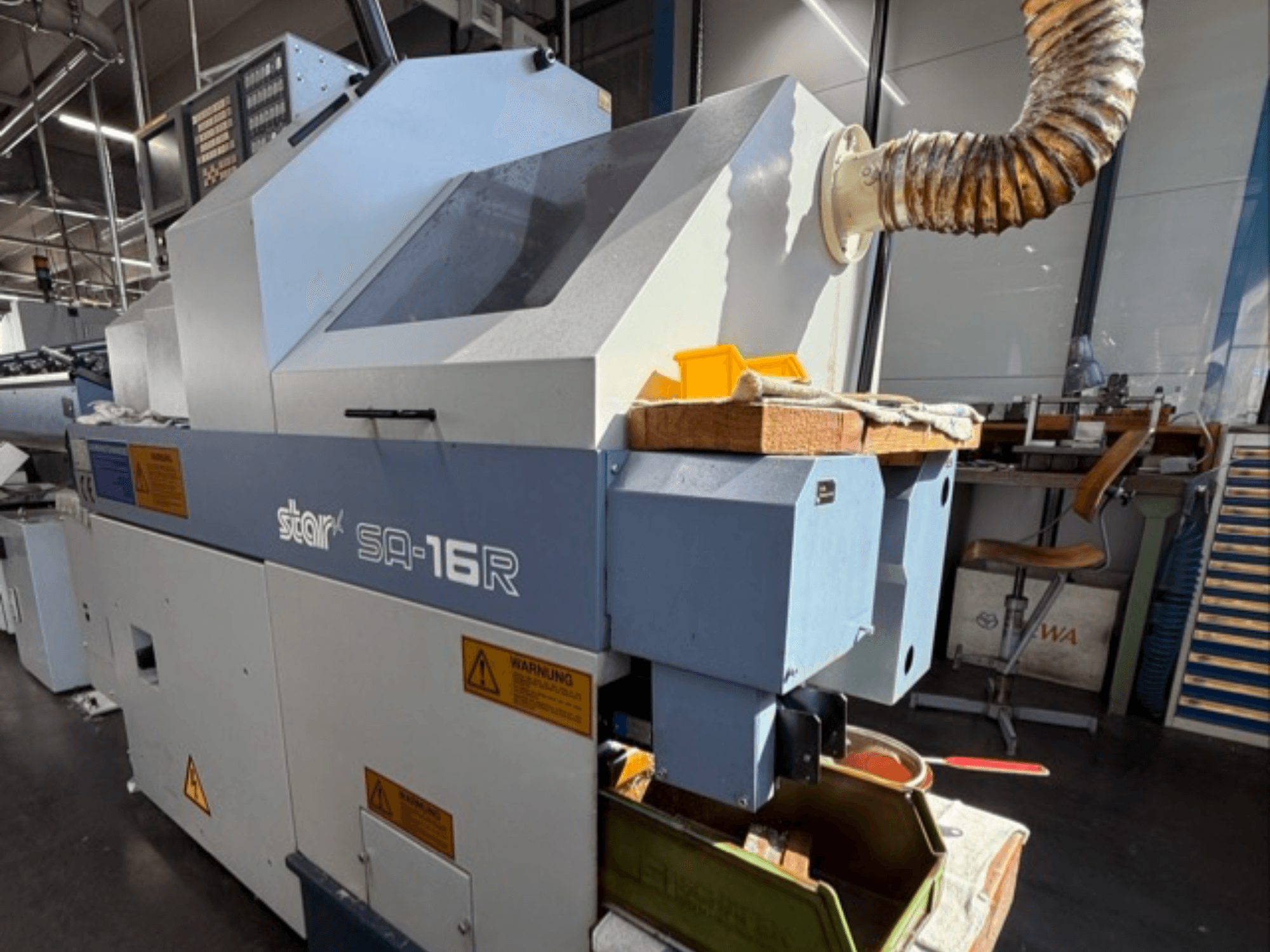 Stark SA-16R mašīna, skatoties no priekšpuses, ar konusveida izplūdes atveri un darba vietu ar dzelteniem darbarīkiem un brīdinājuma uzlīmēm.