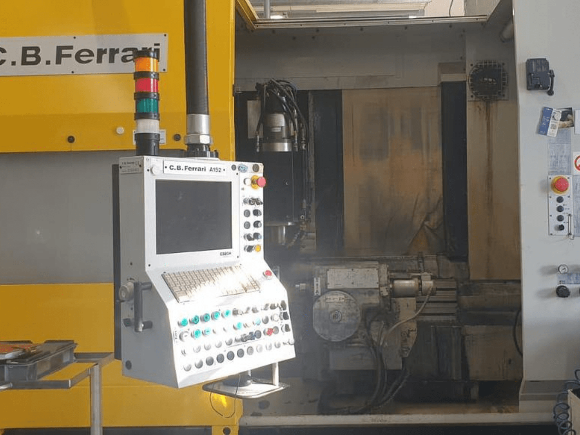 C.B. Ferrari A152 vertikālās apstrādes centra priekšējais skats, kurā redzams vadības panelis ar pogām un mašīnas motora komponentiem.