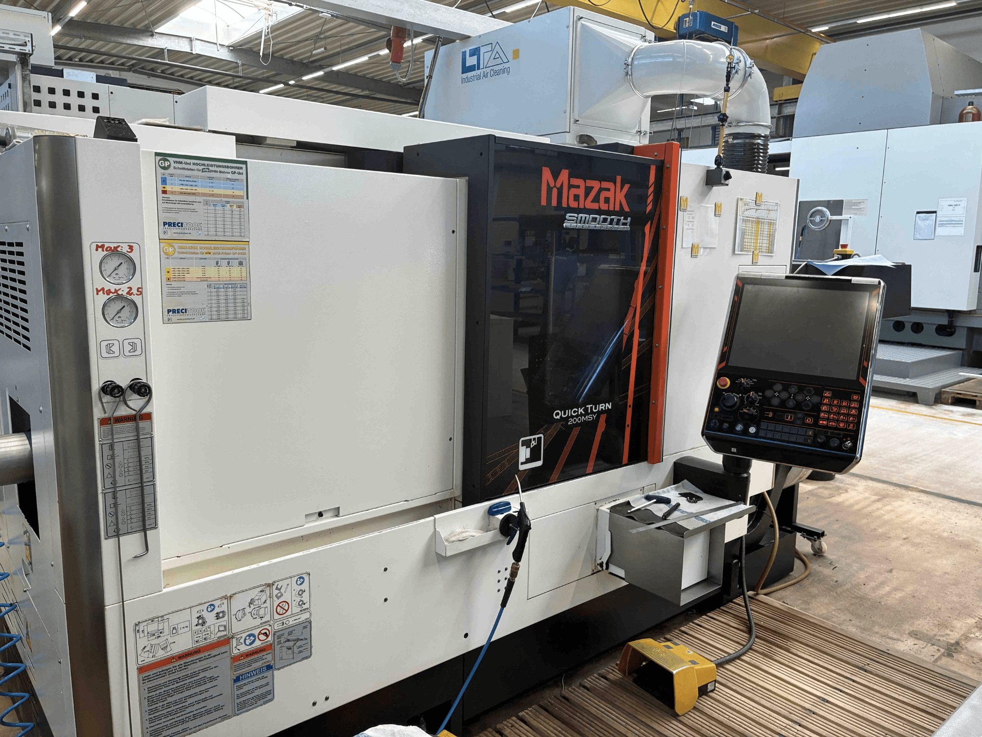Mazak Quick Turn Smooth 200MSY frēzēšanas centrs, priekšējais skats, kurā redzams vadības panelis un darba mērinstrumenti.