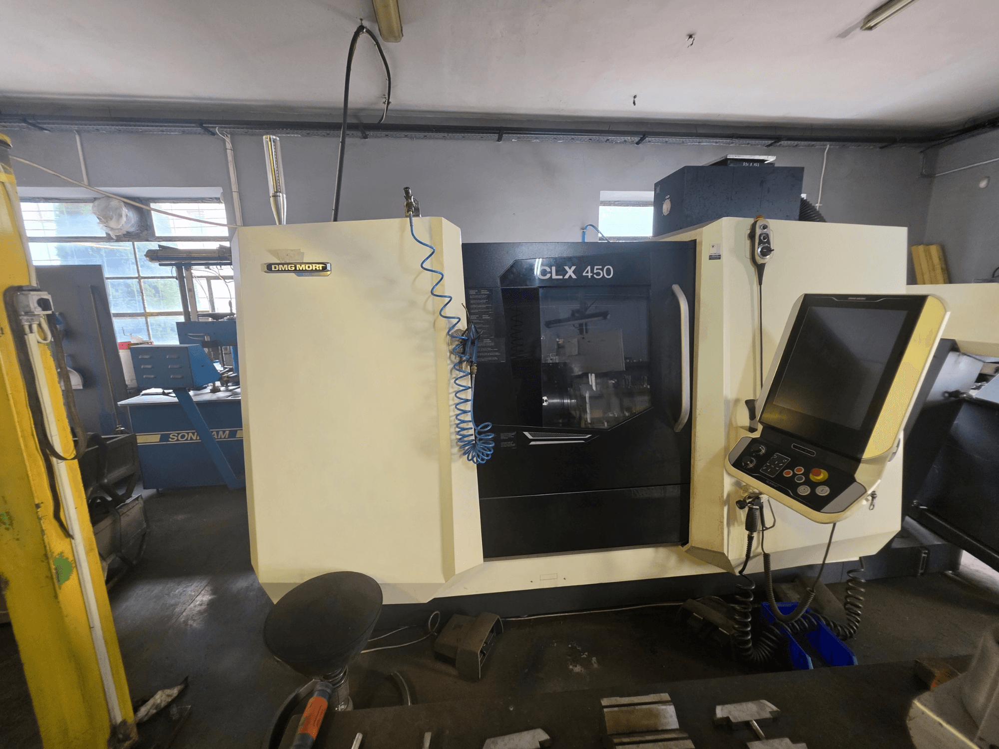 DMG MORI CLX 450 V6 horizontālā virpošanas mašīna, skats no priekšpuses, kurā redzams vadības panelis un zīmola logotips.