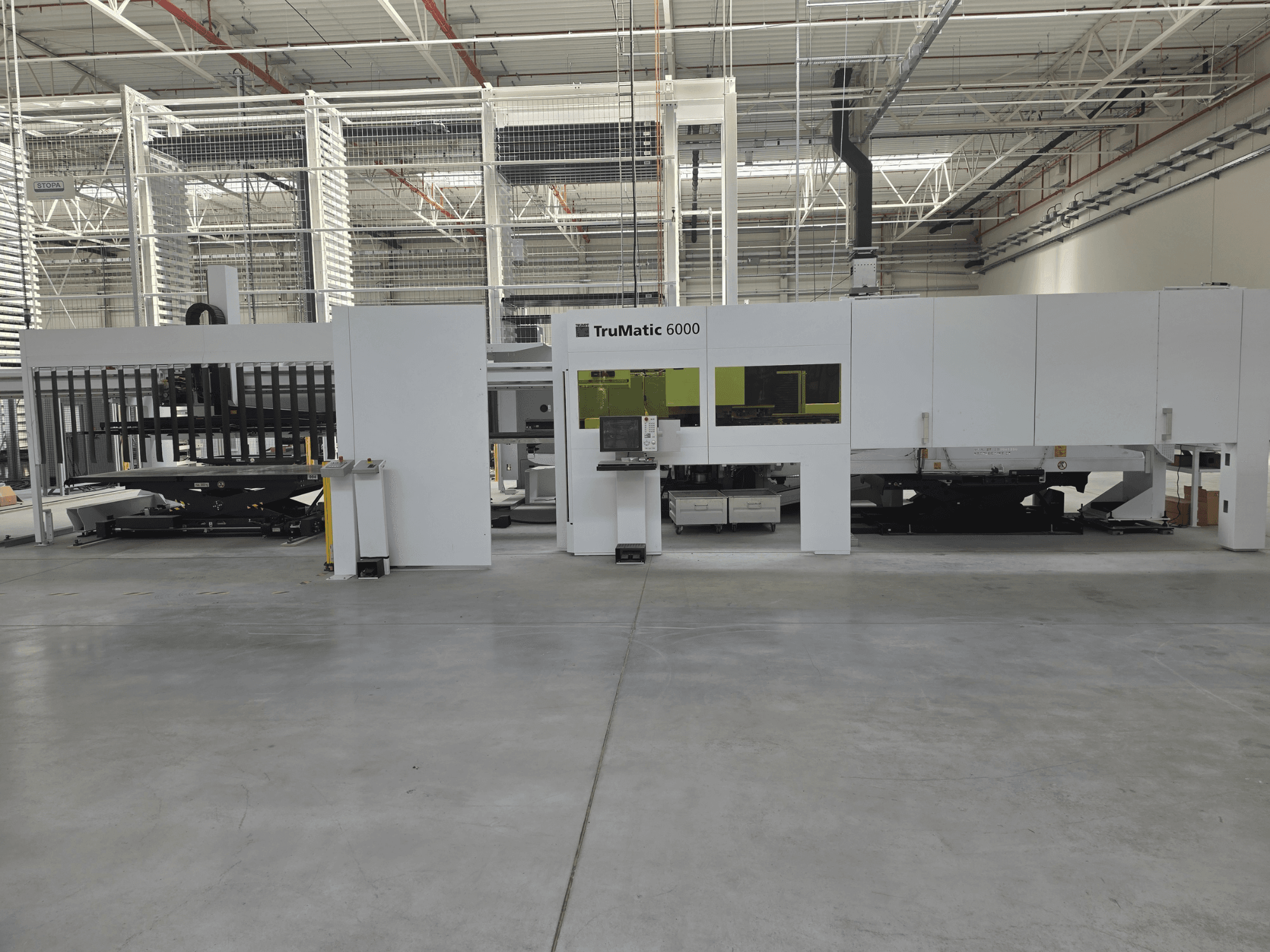 TRUMPF TruMatic 6000 automatizētā metāla lokšņu apstrādes sistēma, skats no priekšpuses, kurā redzams vadības panelis un iekraušanas zona.