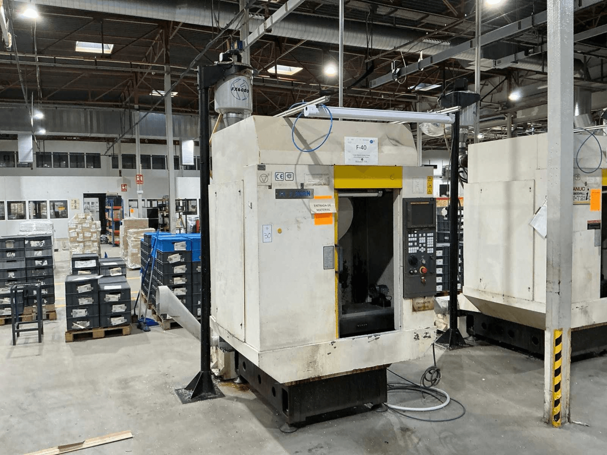 FANUC ROBODRILL α-T21iD, priekšējais skats uz vertikālo apstrādes centru rūpnieciskā vidē, redzamas vadības paneļa detaļas.