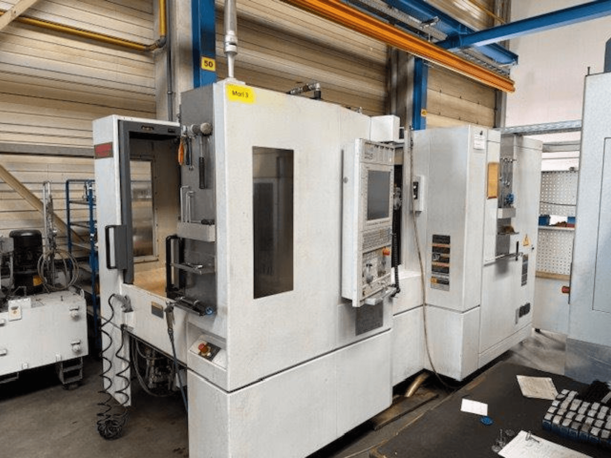 MORI SEIKI NH4000 DCG horizontālā apstrādes centra priekšējais skats ar atvērtām durvīm un vadības paneli, kurā redzama darba telpa.