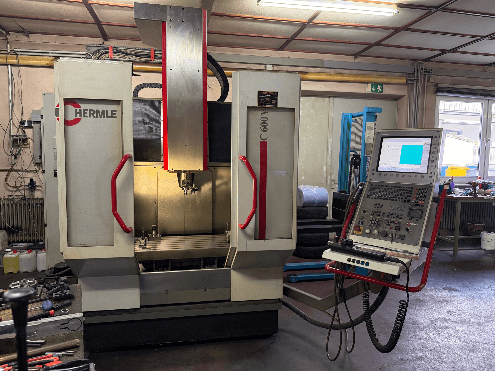 Hermle C 600 CNC frēzmašīna no priekšpuses, ar vadības paneli ar daudzām pogām un plašu darba zonu.