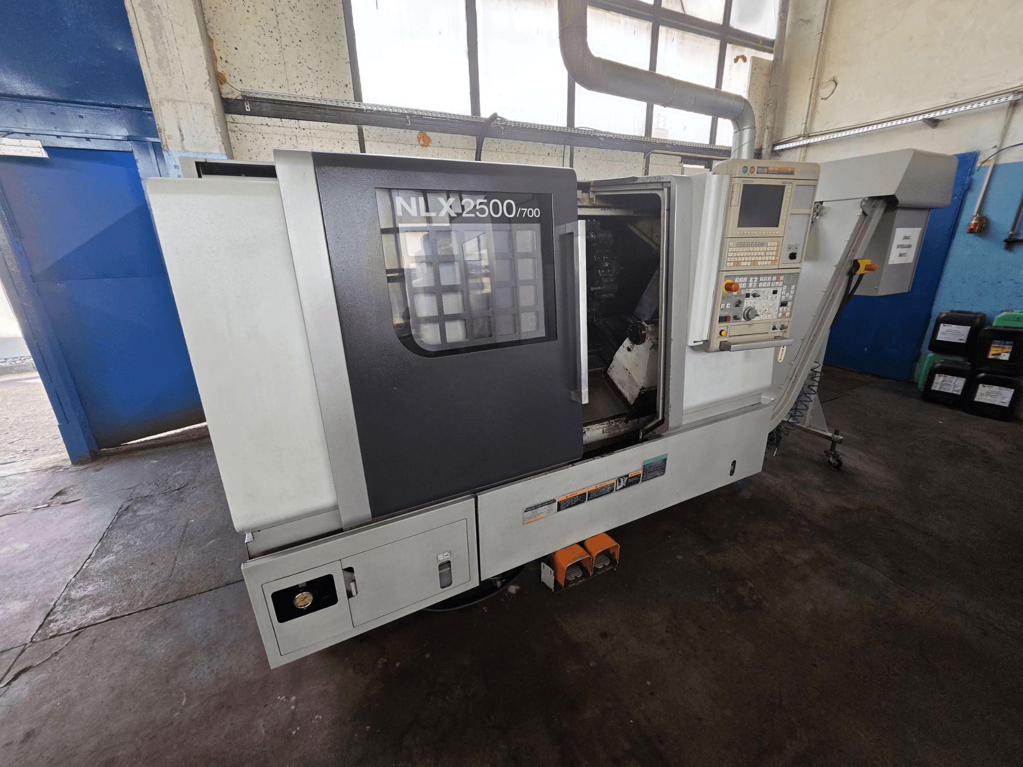 DMG MORI NLX 2500/700 horizontālā virpošanas mašīna sānskatā, kurā redzams vadības panelis un apstrādes zona.