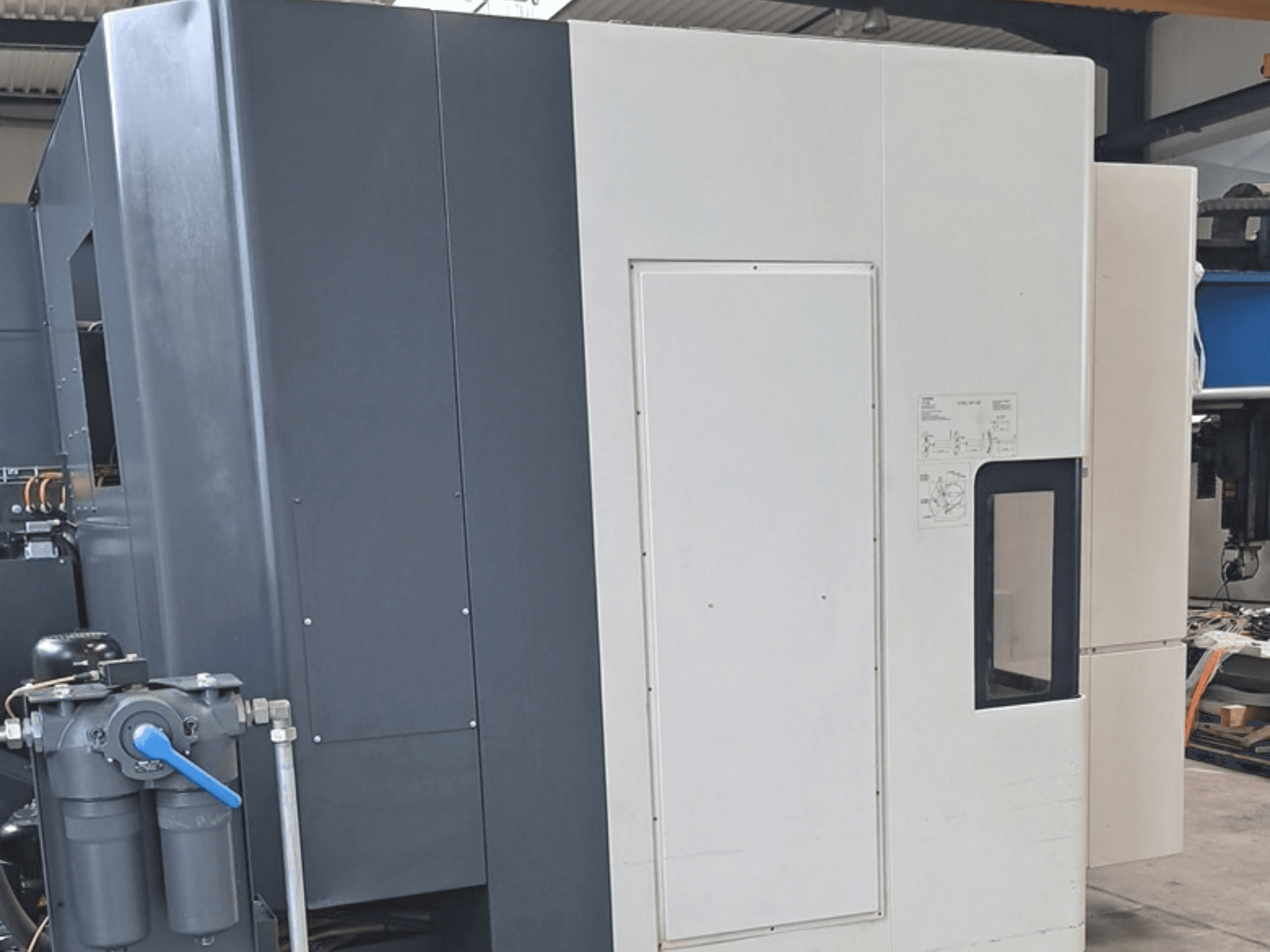 DMG MORI NHX5000 horizontālais apstrādes centrs, sānskats, kurā redzams vadības panelis un mehāniskās detaļas.