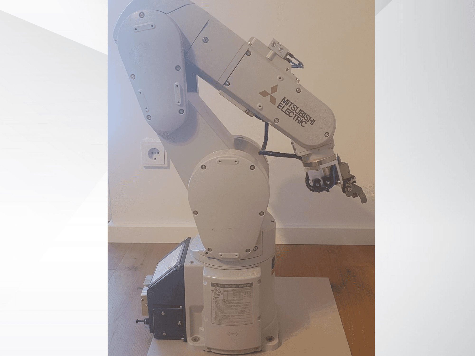 Mitsubishi Electric robotizētā roka, skats no sāniem, ar satvērēju un detalizētu vadības paneli uz pamatnes darbības iestatījumiem.