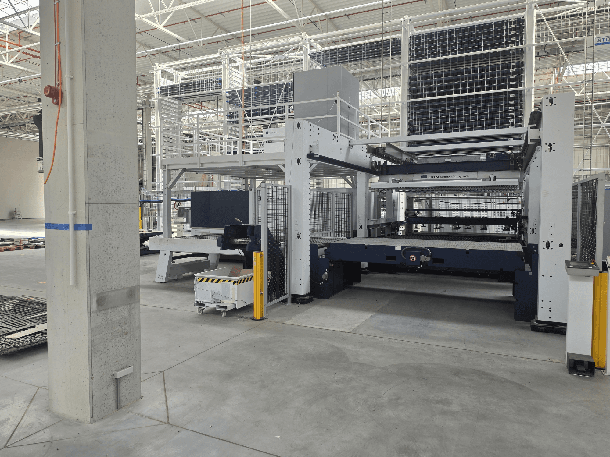 TRUMPF TruLaser 5030 fiber L76 FMC skats no priekšpuses, kurā redzama šķiedru lāzera griešanas iekārta plašā rūpnieciskā vidē.