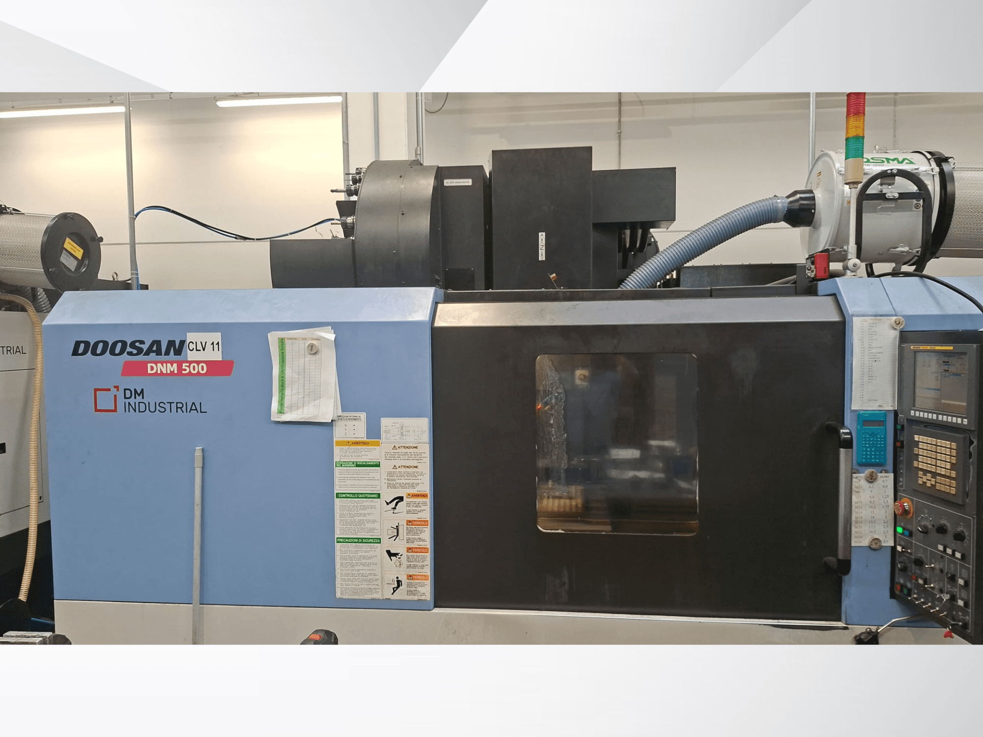 DOOSAN DNM 500 vertikālais apstrādes centrs no sāniem, kurā redzama vadības paneļa un darbības detaļas.