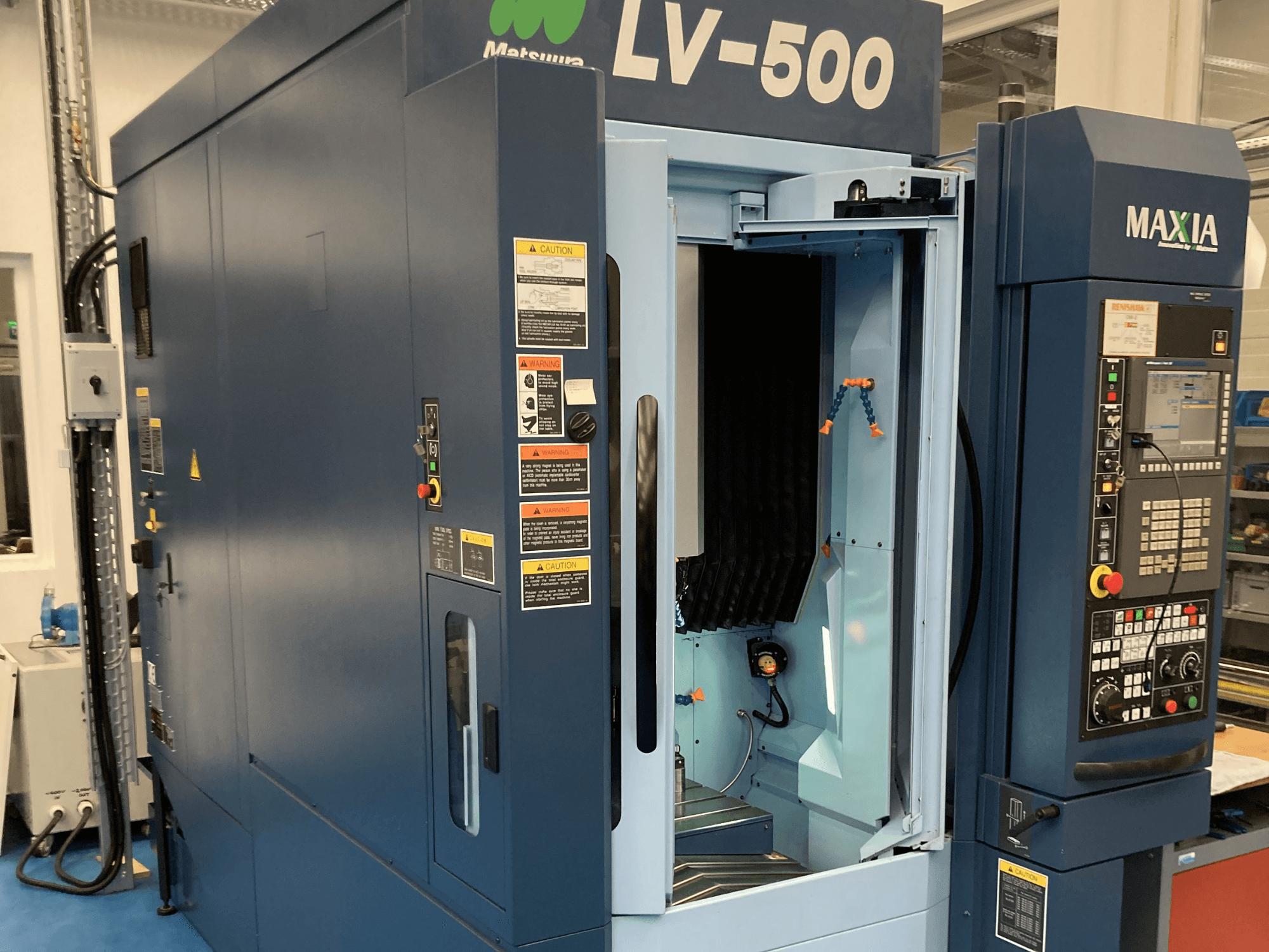 Matsuura LV-500 vertikālais apstrādes centrs no priekšpuses, ar atvērtām durvīm un vadības paneli ar pogām.