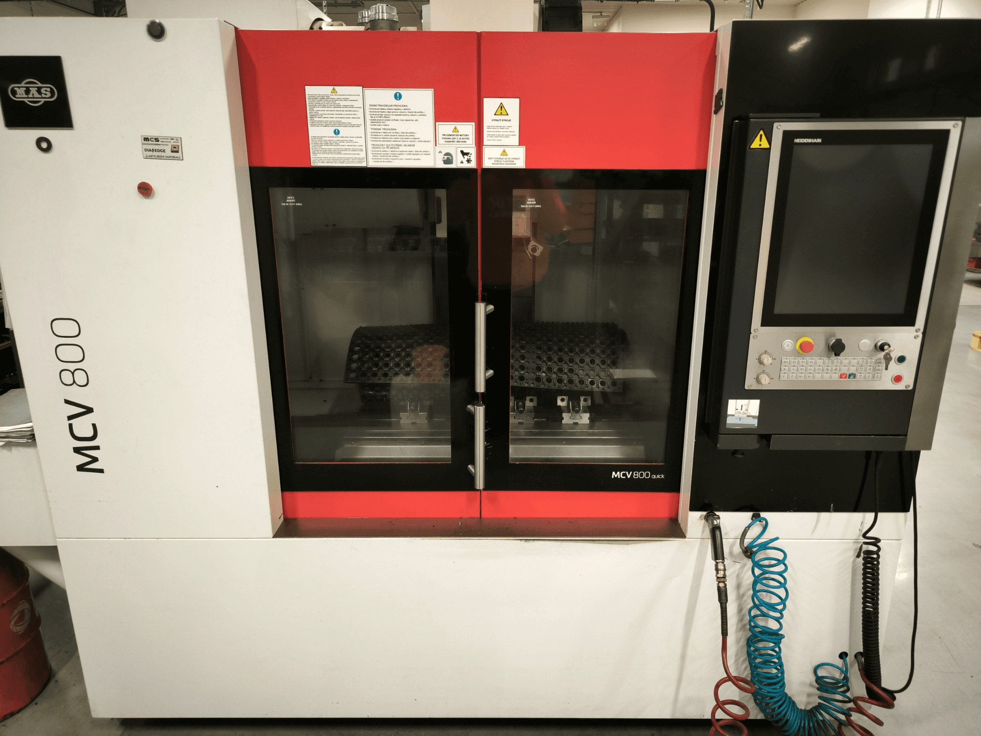 Vertikālais apstrādes centrs KOVOSVIT MAS MCV 800 QUICK, skats no priekšpuses ar vadības paneli un dubultām stikla durvīm, kurās redzama darba telpa.