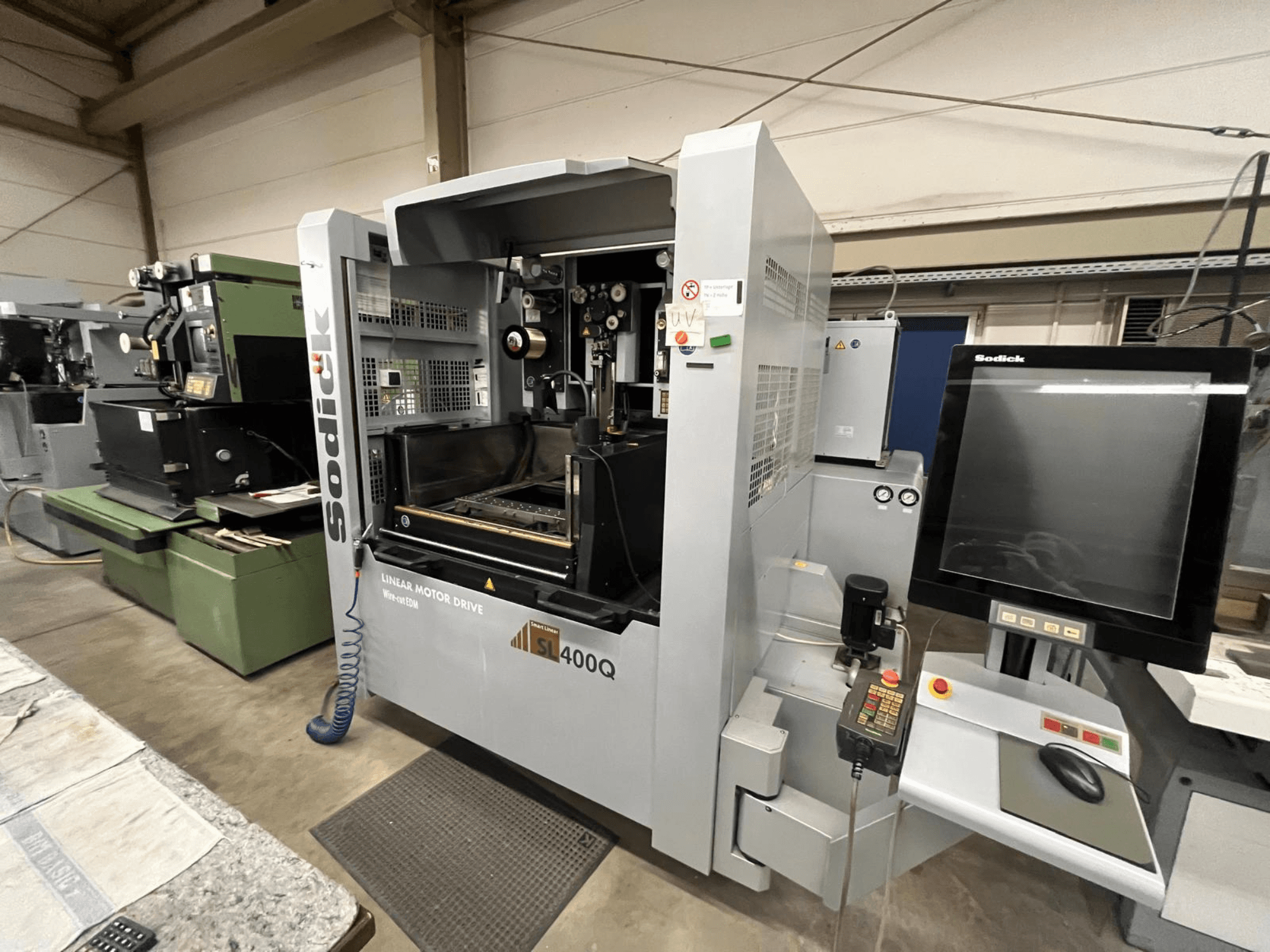 Sodick SL400Q lineārā motora piedziņas CNC darbagalds, priekšējais skats ar digitālo vadības paneli un displeju darbnīcā.