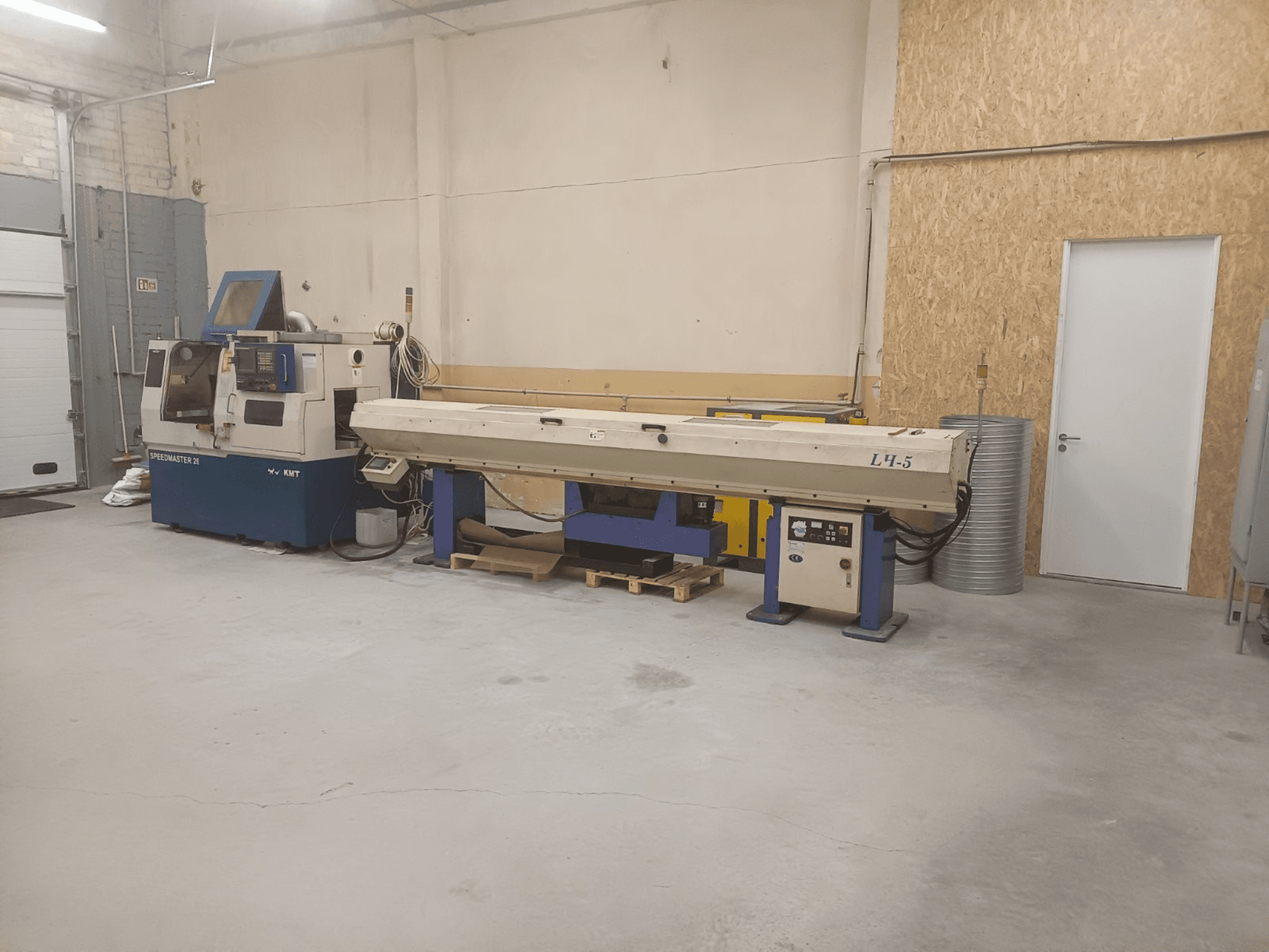 Rūpnieciskā darbnīca ar KMT Speedmaster 34 mašīnu un L4.5, skatoties no priekšpuses, ar redzamām vadības ierīcēm un iekārtām.