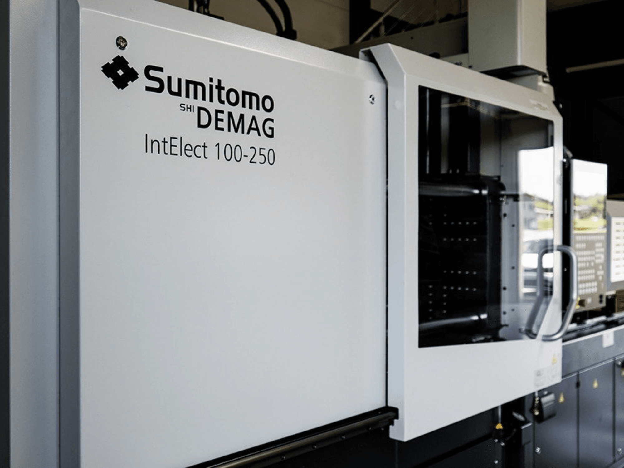 SUMITOMO SHI DEMAG IntElect 100/250 elektriskās injekcijas liešanas mašīnas skats no priekšpuses ar vadības paneli un drošības ierīcēm.