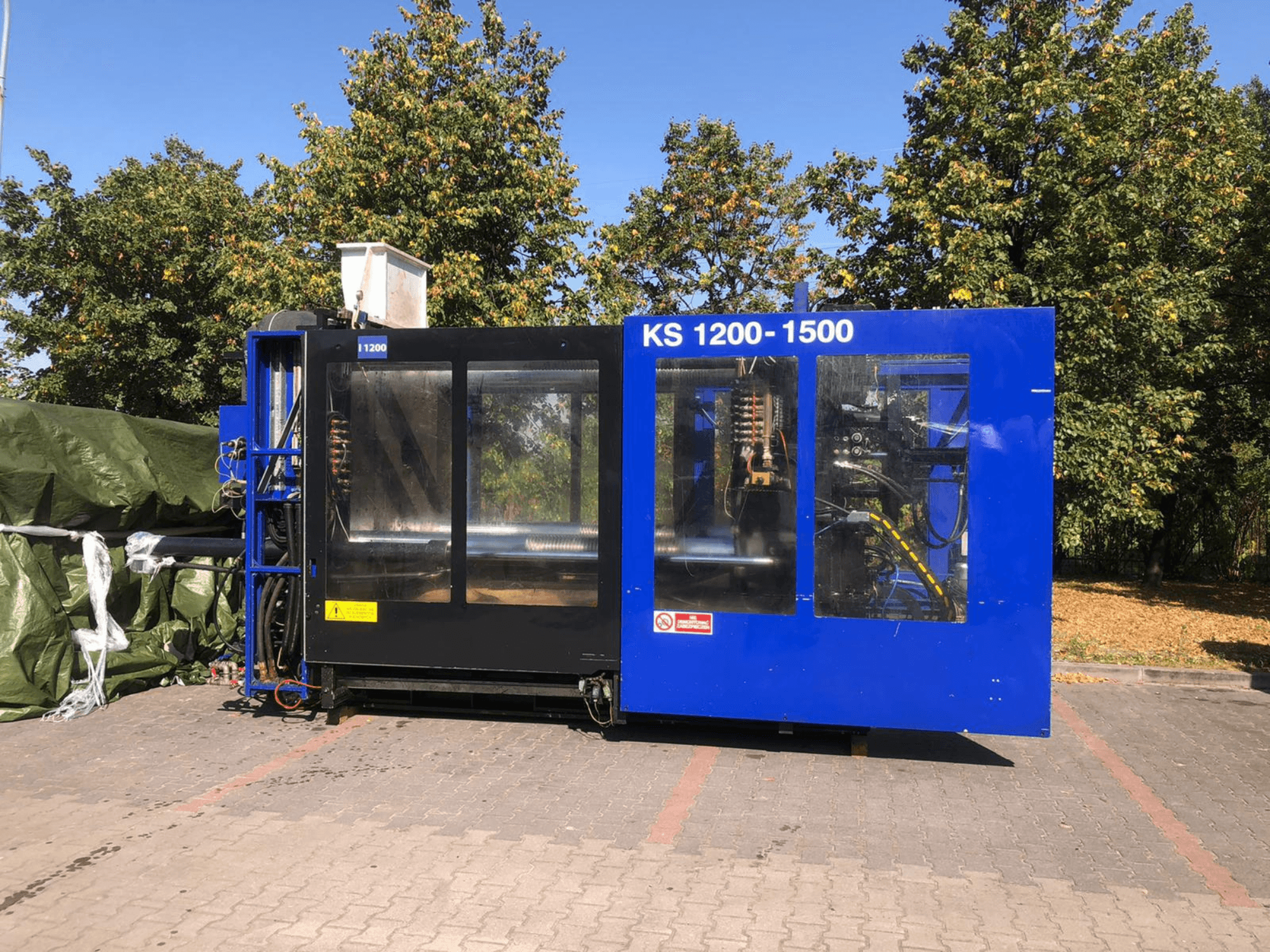 Hidrauliskā iesmidzināšanas iekārta ITALTECH KS 1200 8300 ES, skats no sāniem, kurā redzamas vadības ierīces un mašīnas detaļas parka vidē.